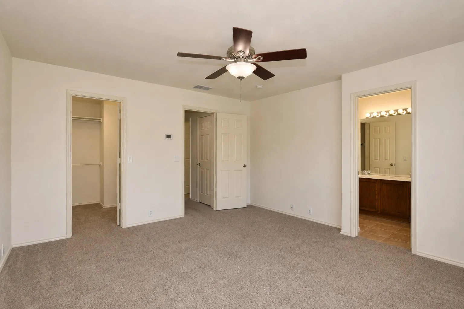 Neutral tone wall finishes, ceiling fan with integrated lighting, carpeted flooring, and built-in closet storage