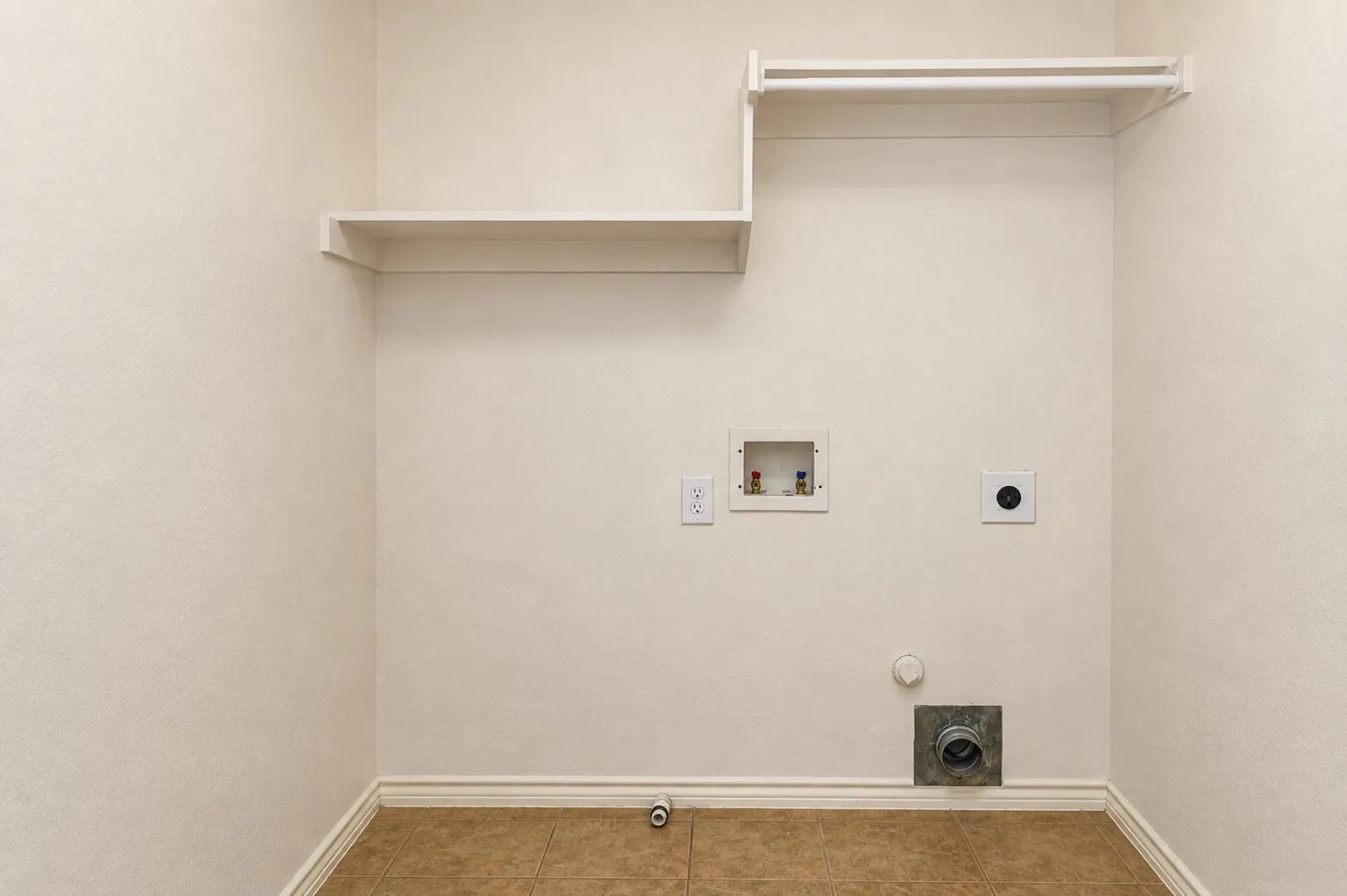 Built-in shelving, hanging rod, wall-mounted electrical outlets, and tile flooring