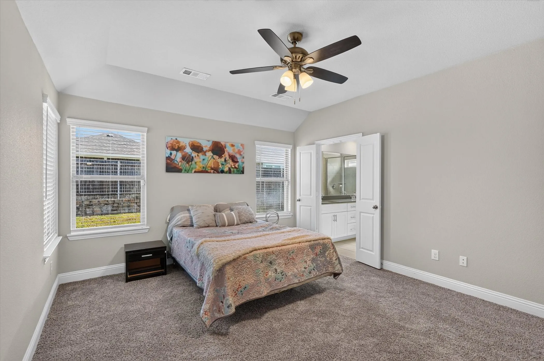 Vaulted ceiling, ceiling fan with integrated lighting, two windows with blinds, carpeted flooring, and a double-door entry