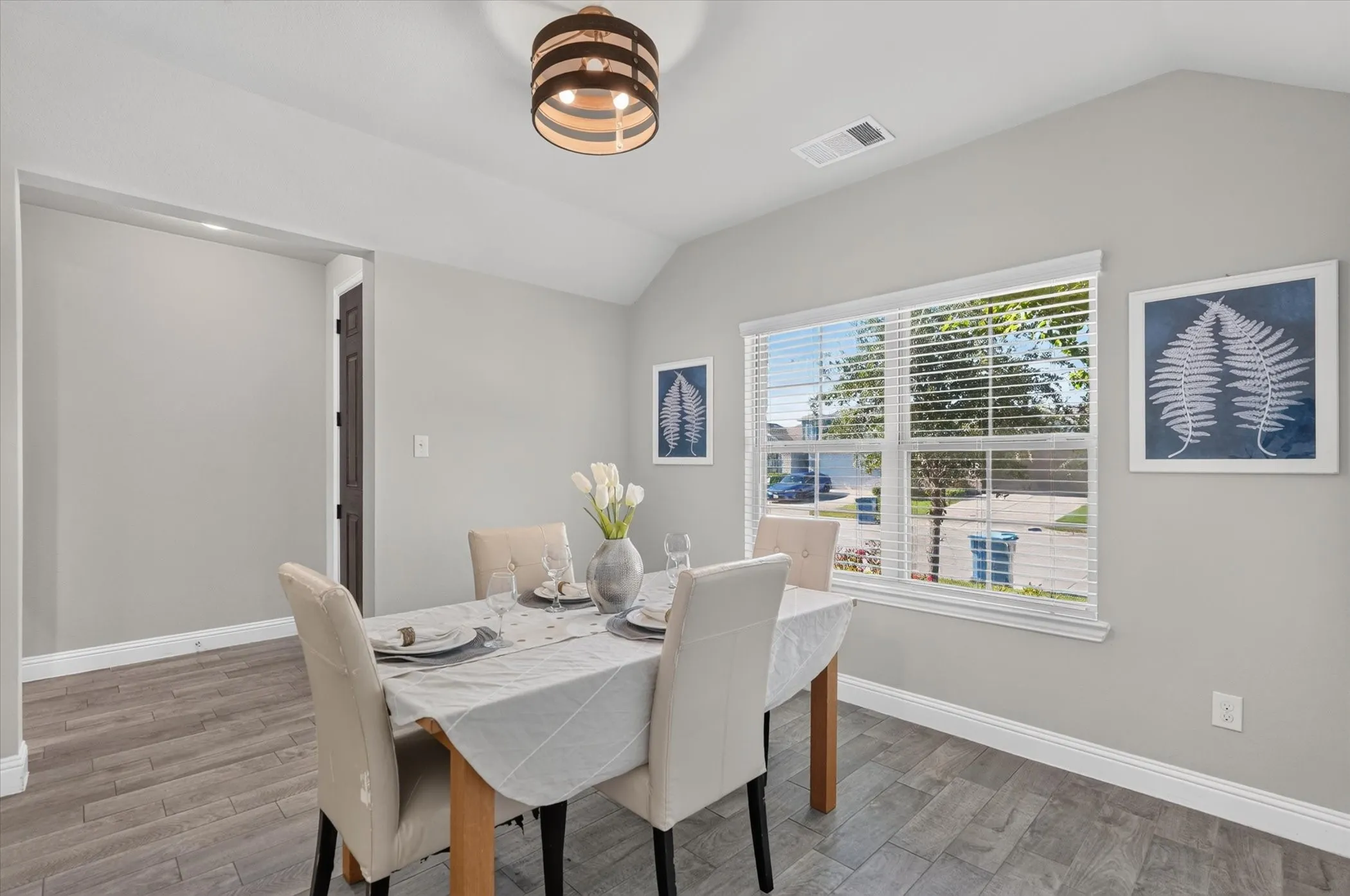 Bright dining space featuring large windows with plantation shutters, wood-finish flooring, and a modern ceiling fixture