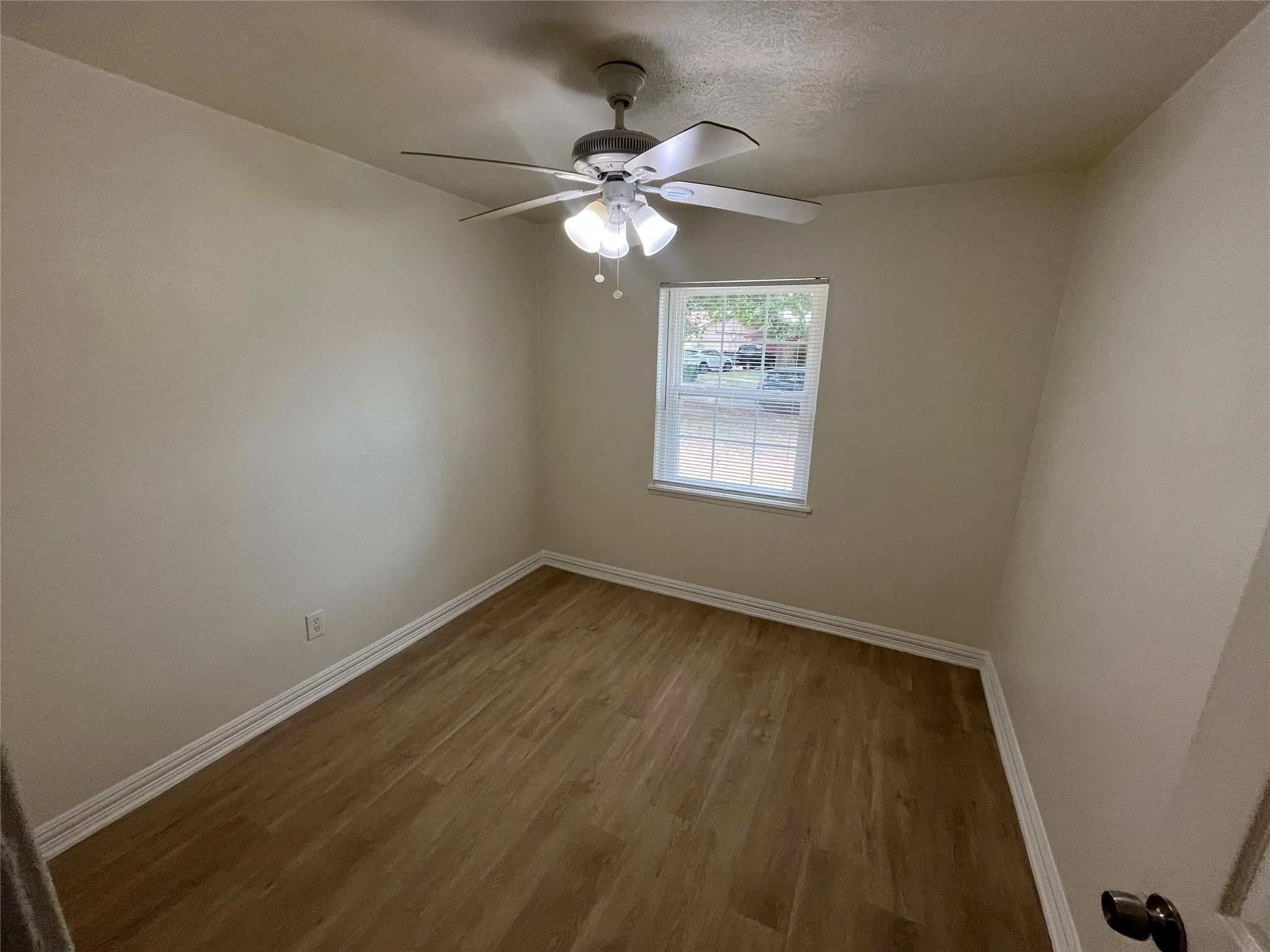 Wood-finish flooring, white trim, and a ceiling fan with integrated lighting