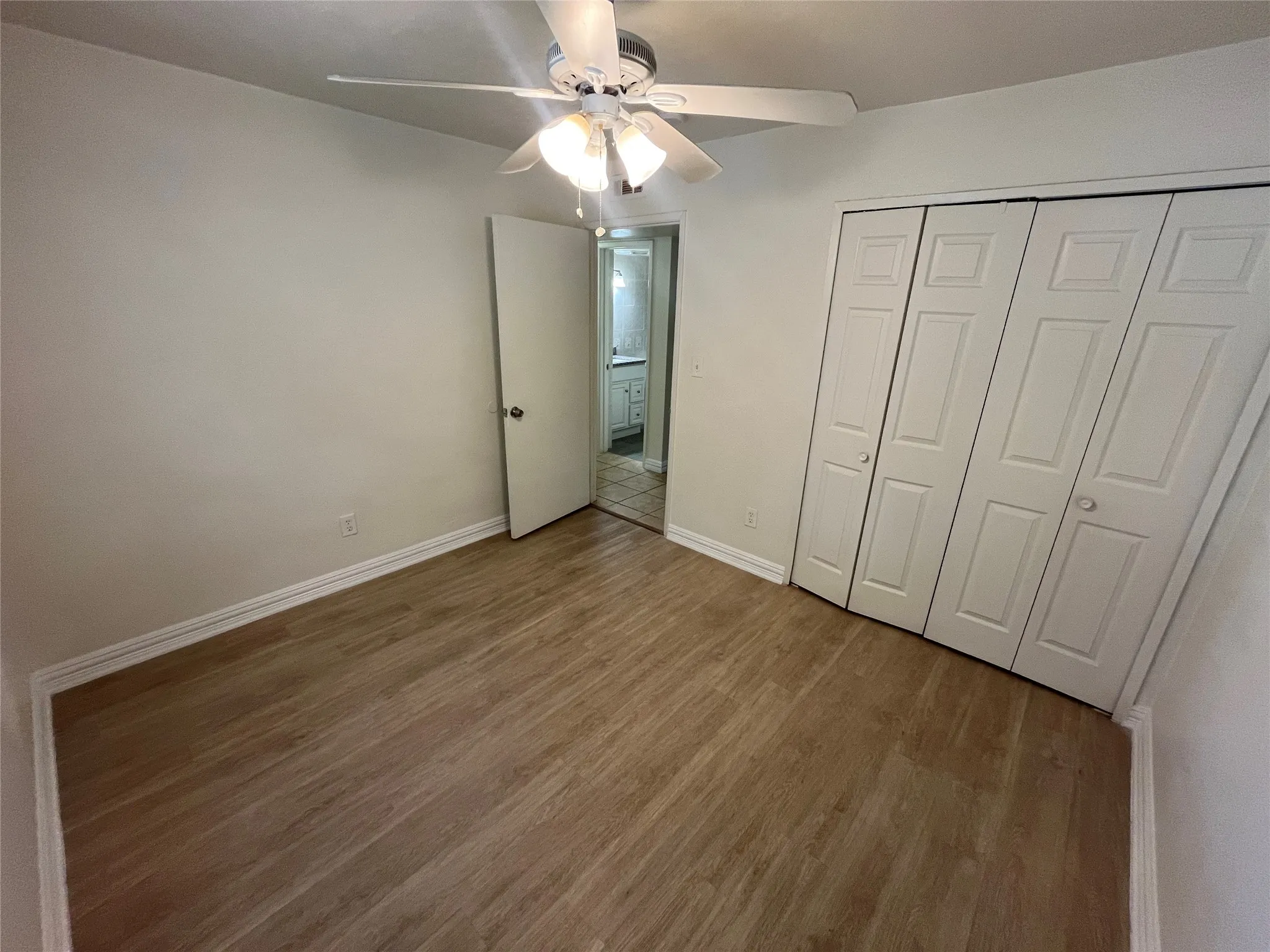 Wood-finish flooring, ceiling fan with integrated lighting, and bi-fold closet doors