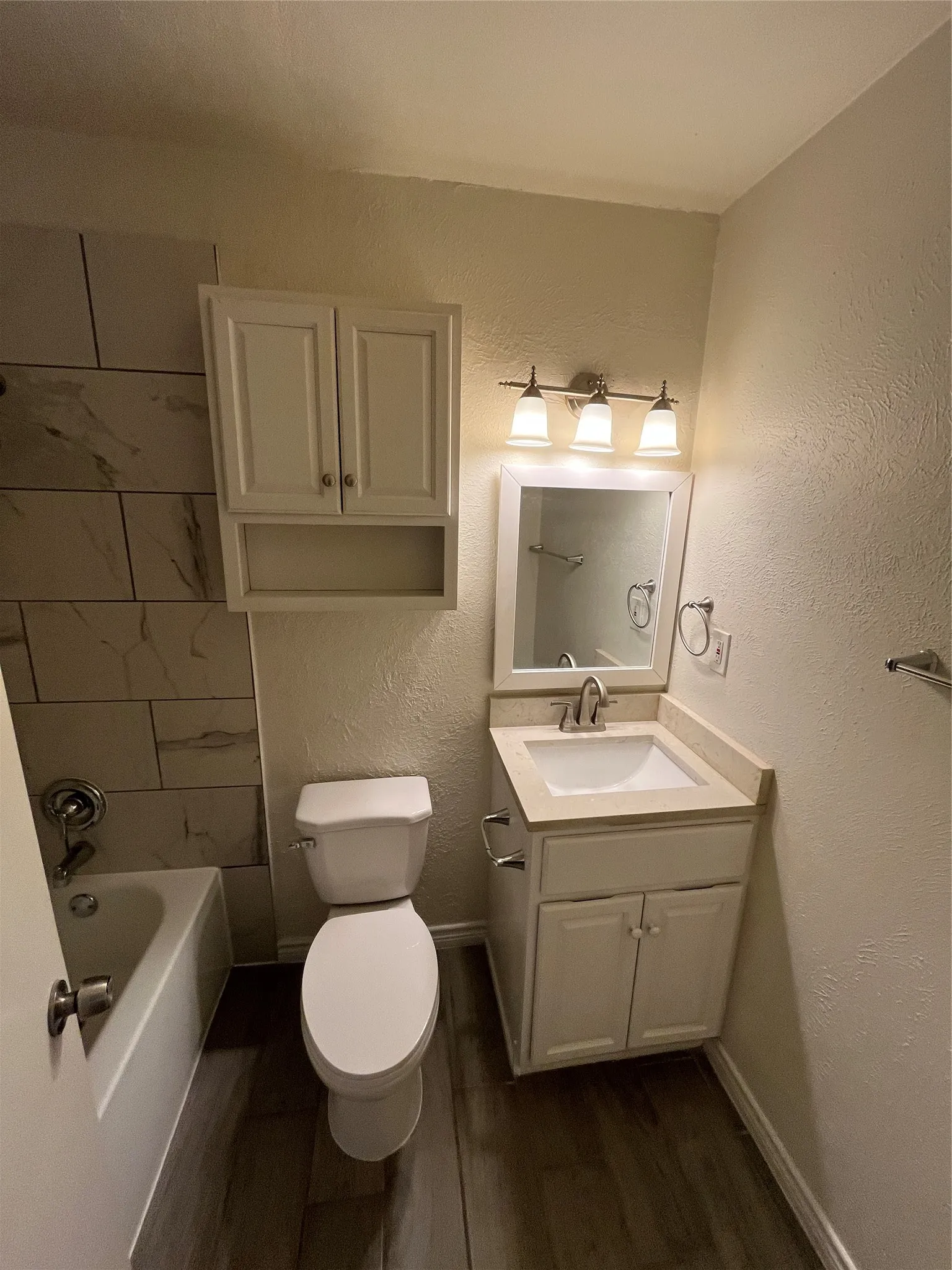 Bathroom featuring a vanity with a white cabinet, under-mount sink, and light-toned countertop