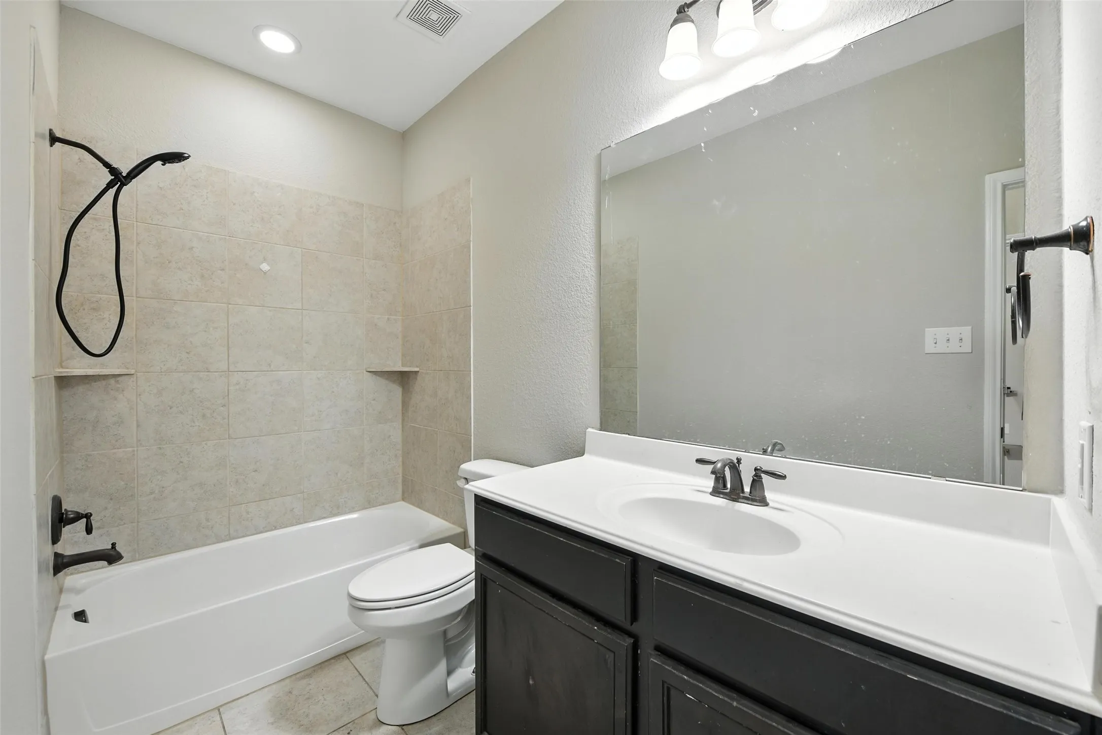 Modern bathroom featuring a dark wood-finish vanity with a white quartz countertop, rectangular undermount sink, and matte black faucet