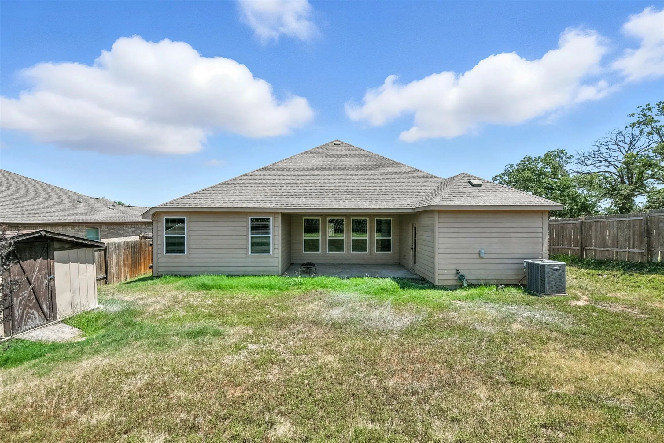 Rear exterior featuring a covered patio, multiple windows, and a fenced perimeter