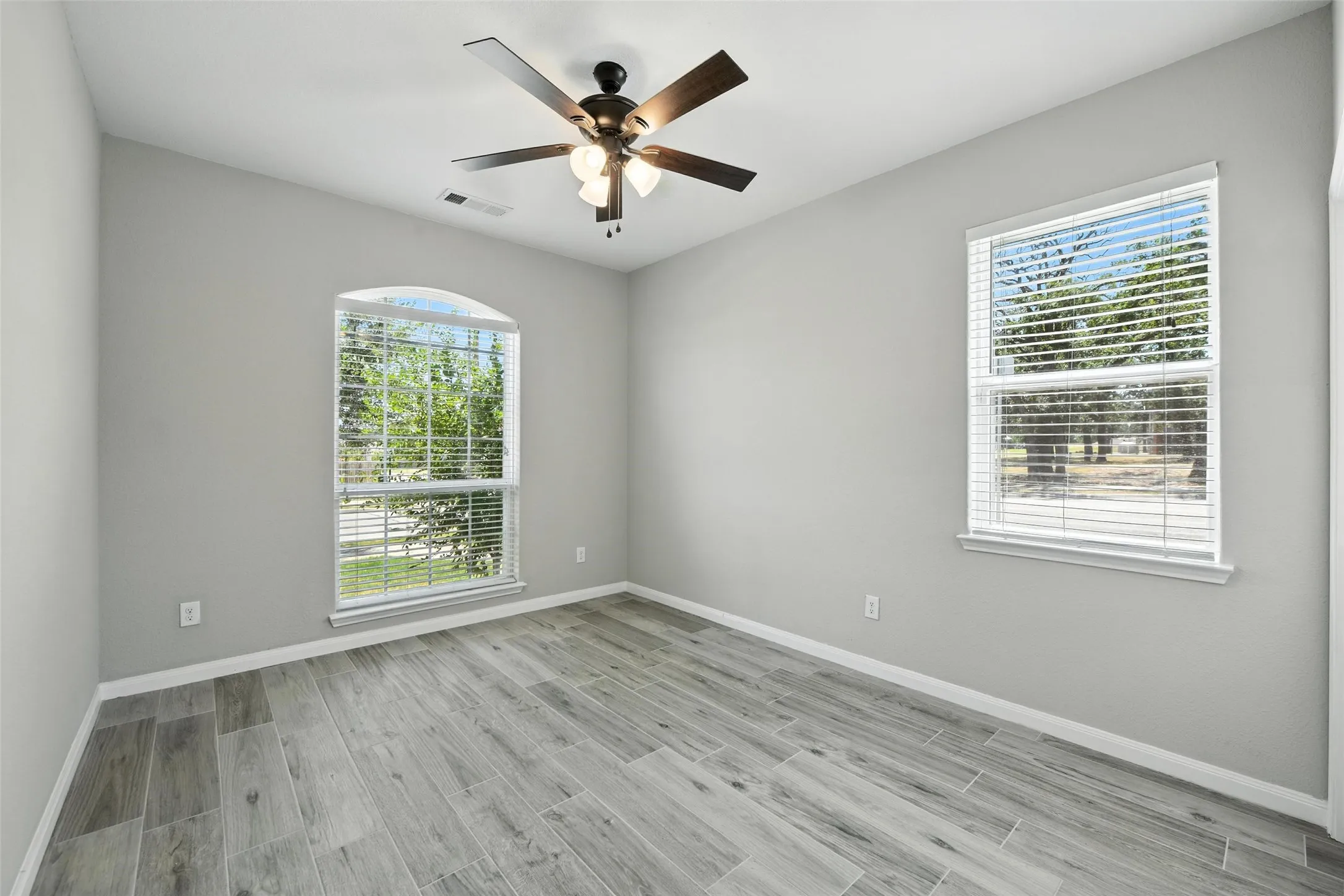 Secondary bedroom with light gray walls and wood-finish tile flooring