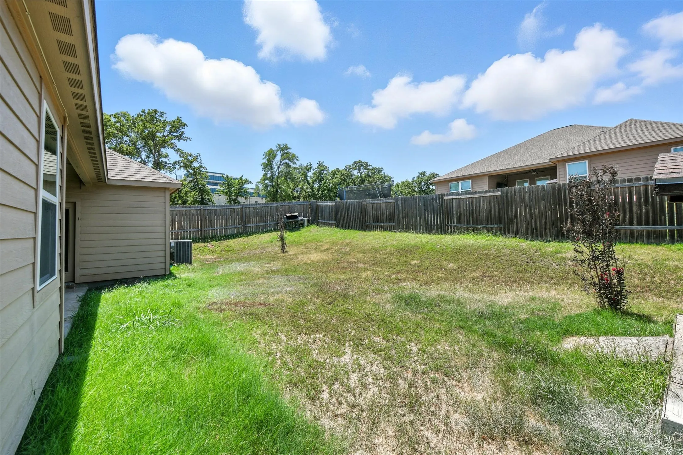Expansive backyard featuring a wood fence perimeter and a partially visible patio area