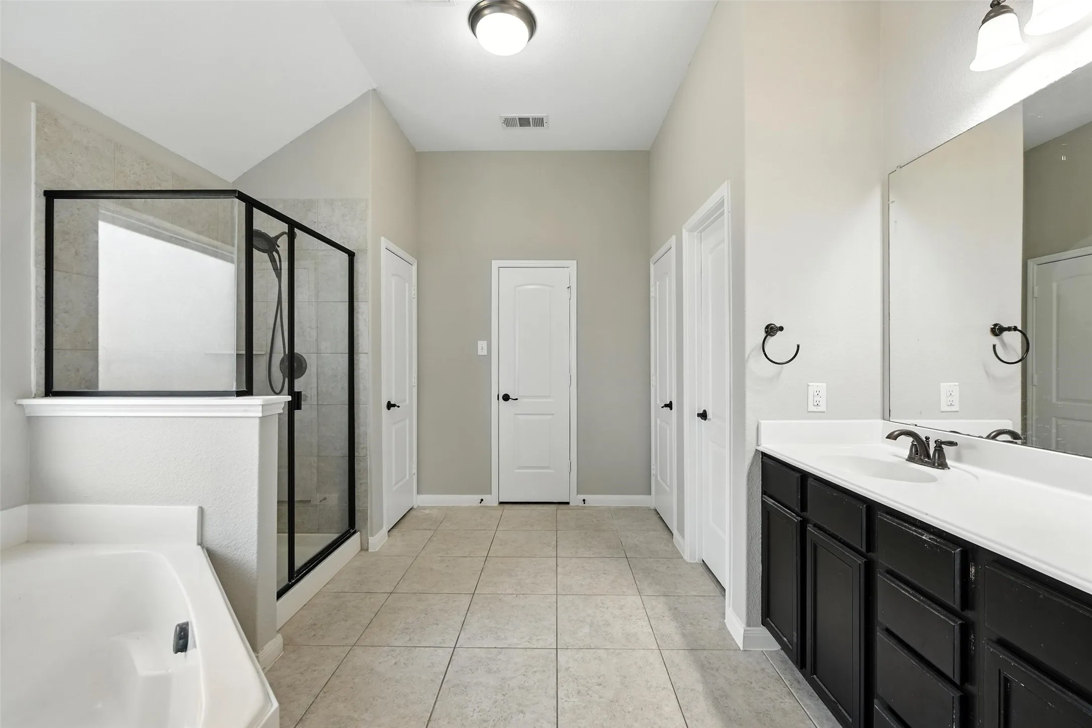 Recessed tub with an adjacent glass-enclosed shower featuring a black frame