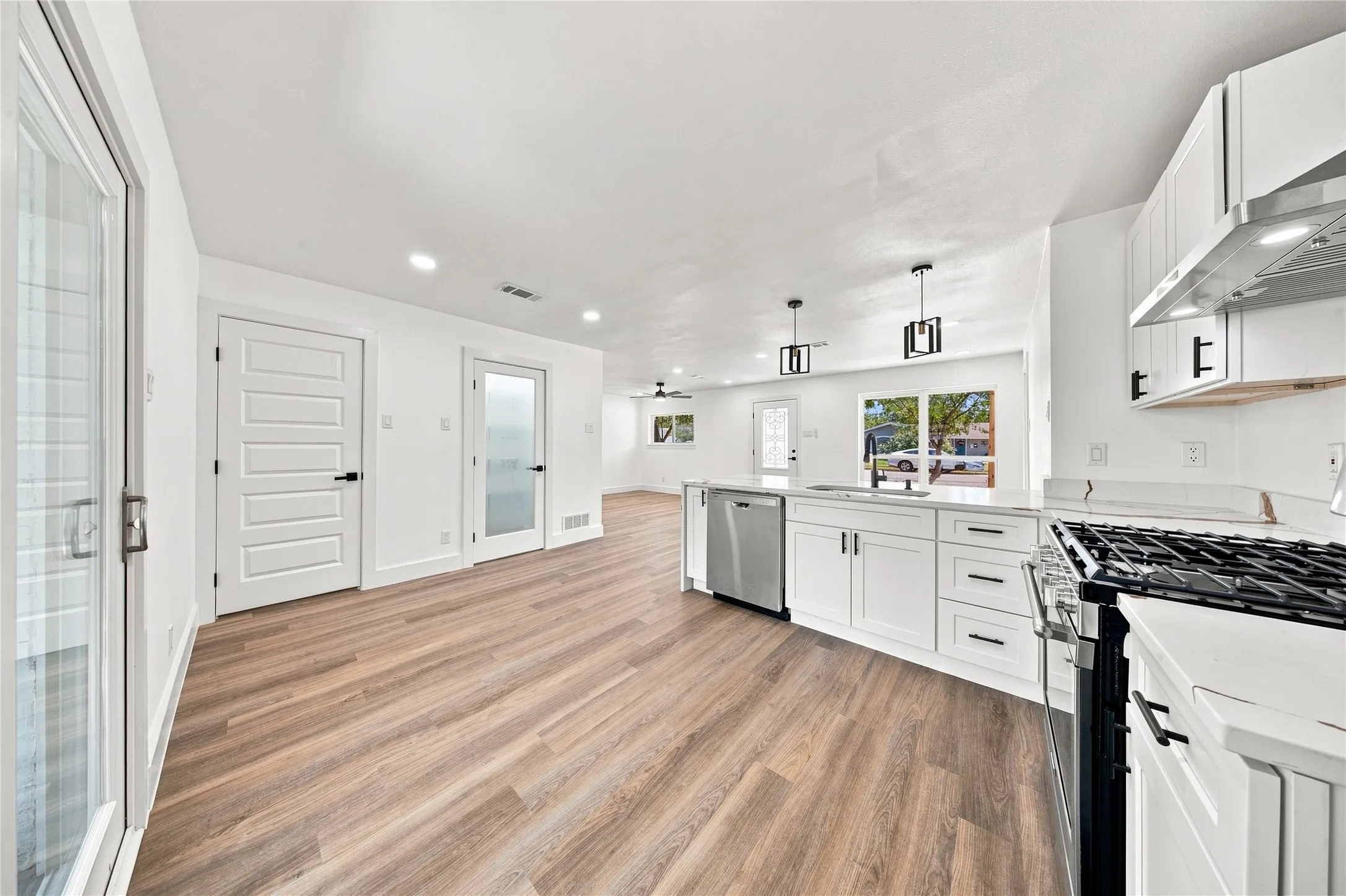 Kitchen featuring white cabinetry, stainless steel appliances, wood-finish flooring, recessed lighting, and a gas range