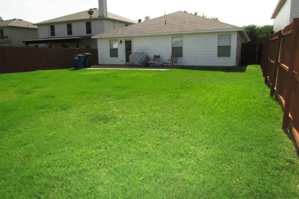 Expansive lawn area, private wood fence, and a concrete patio