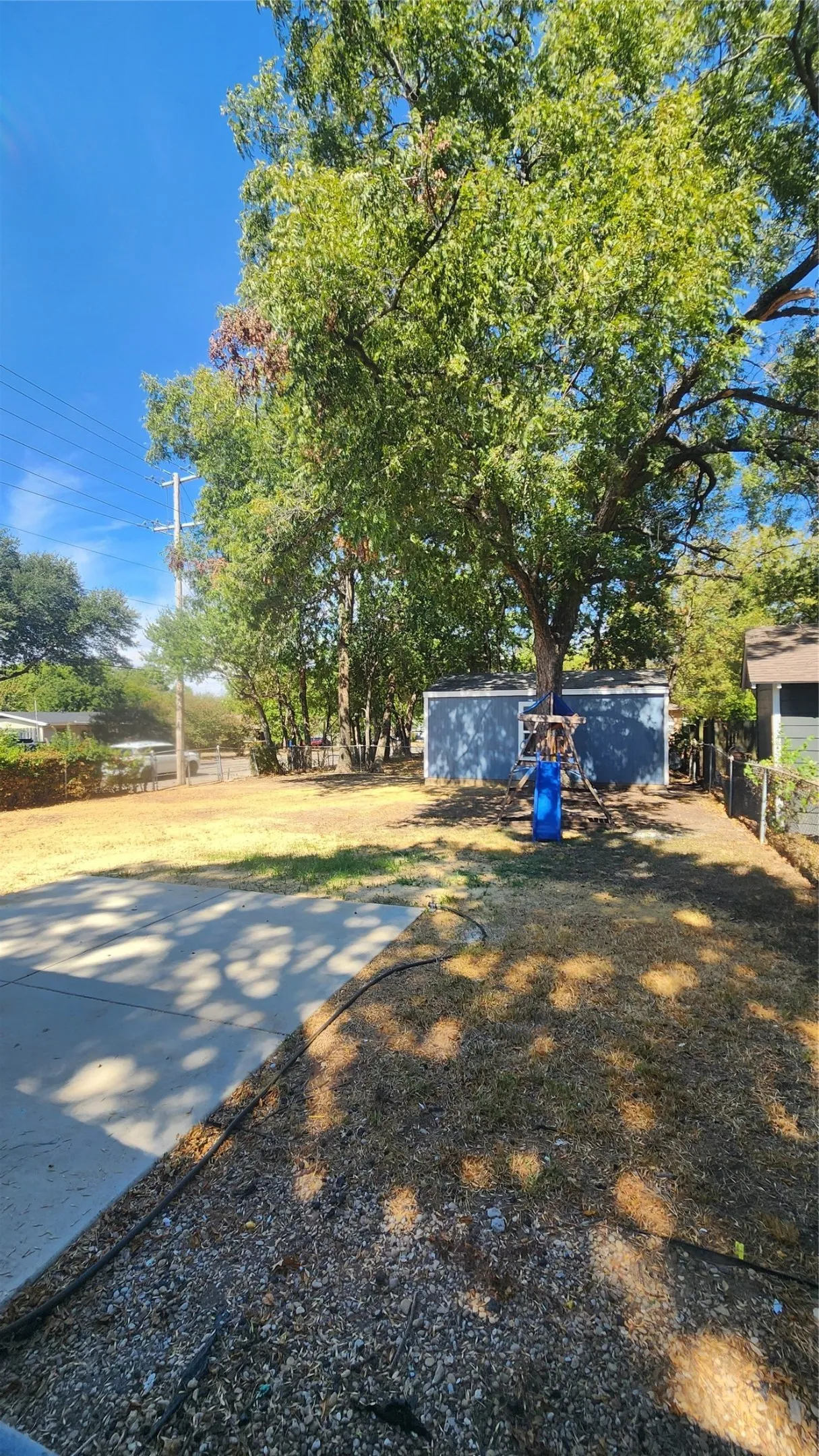 Expansive yard with mature trees, a concrete pad, and a storage shed