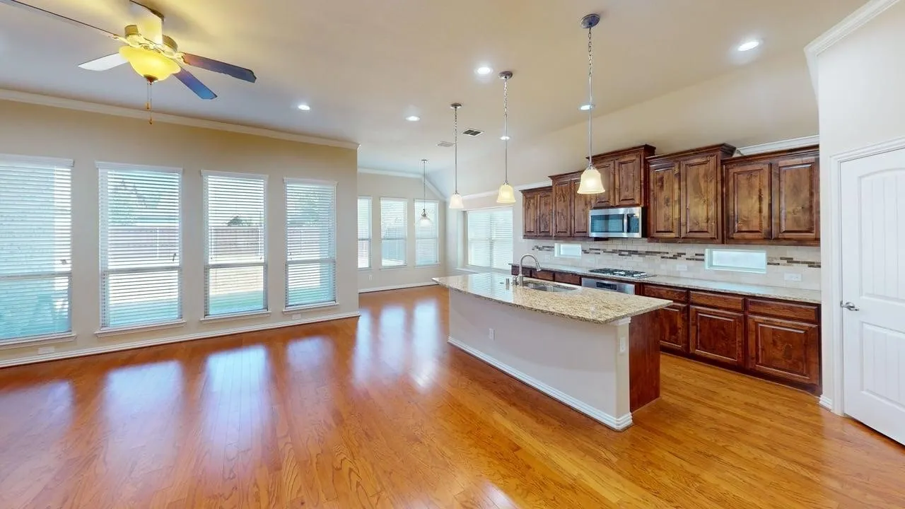 Hardwood-finish flooring throughout, vaulted ceiling, recessed lighting, ceiling fan, and a kitchen island with pendant lighting