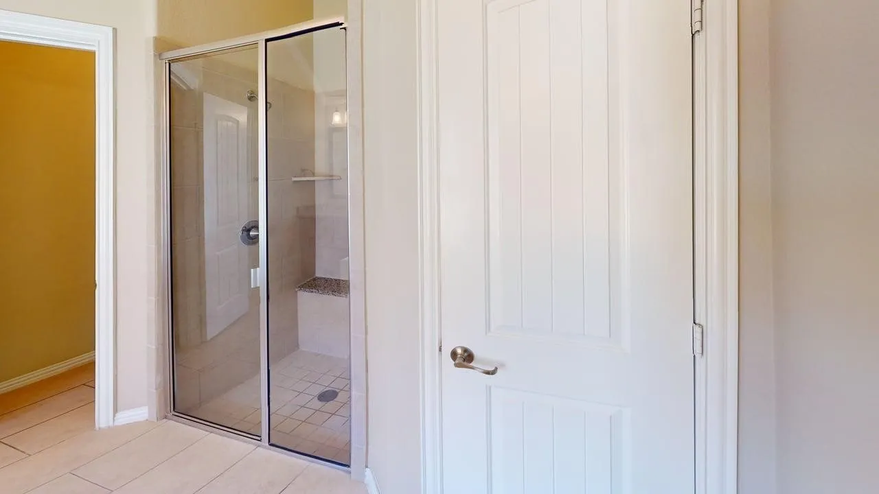 Shower enclosure with sliding glass doors, tiled walls, built-in bench, and tiled flooring