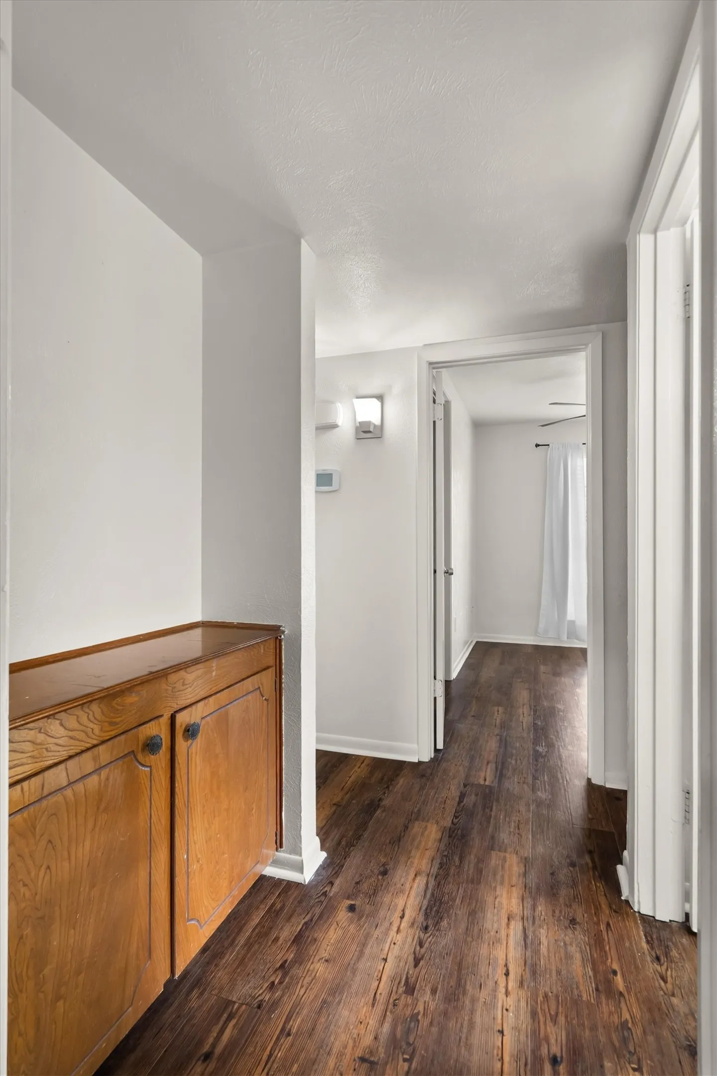 Wood-look flooring throughout, built-in wooden cabinetry, white baseboards, and white painted walls