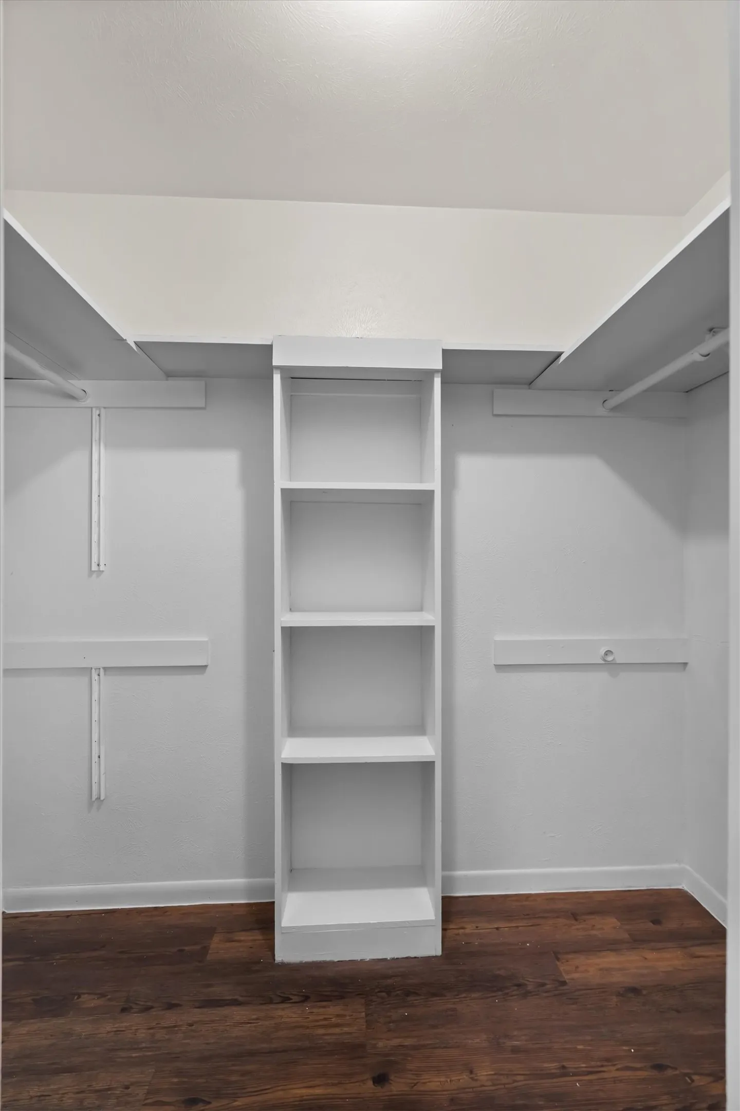 Built-in shelving unit, white walls, wood-look flooring, and integrated clothing rods