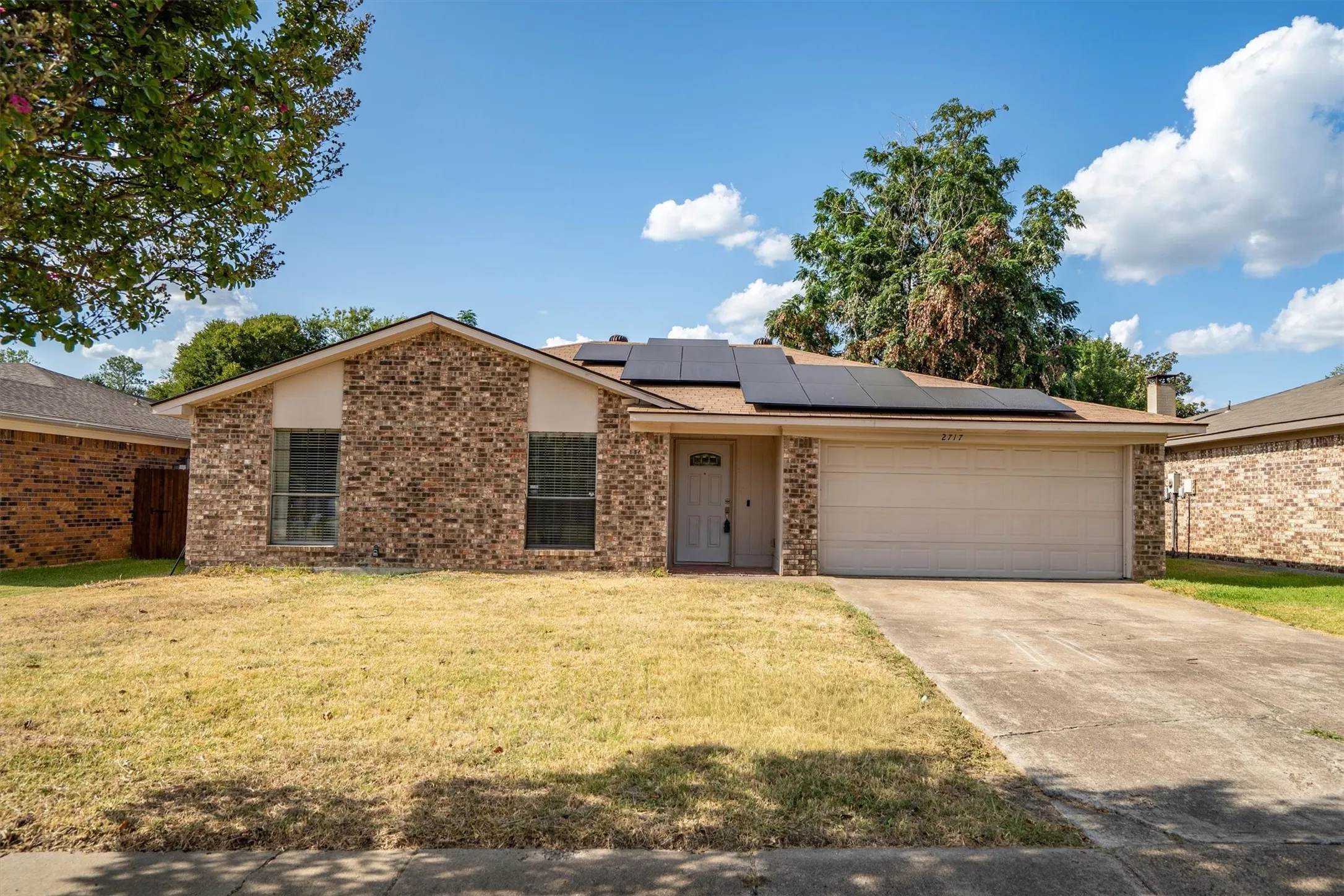 Brick exterior, two-car garage, solar panels, concrete driveway, front entry door