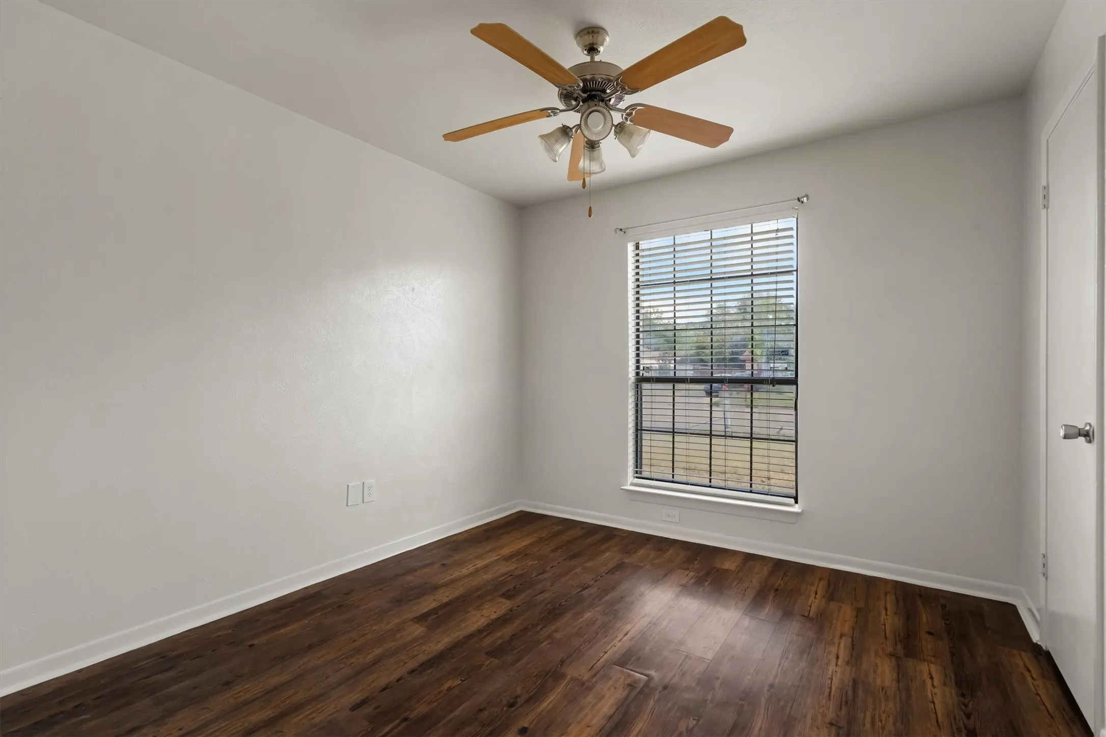 Wood-look flooring with a ceiling fan and a window featuring horizontal blinds