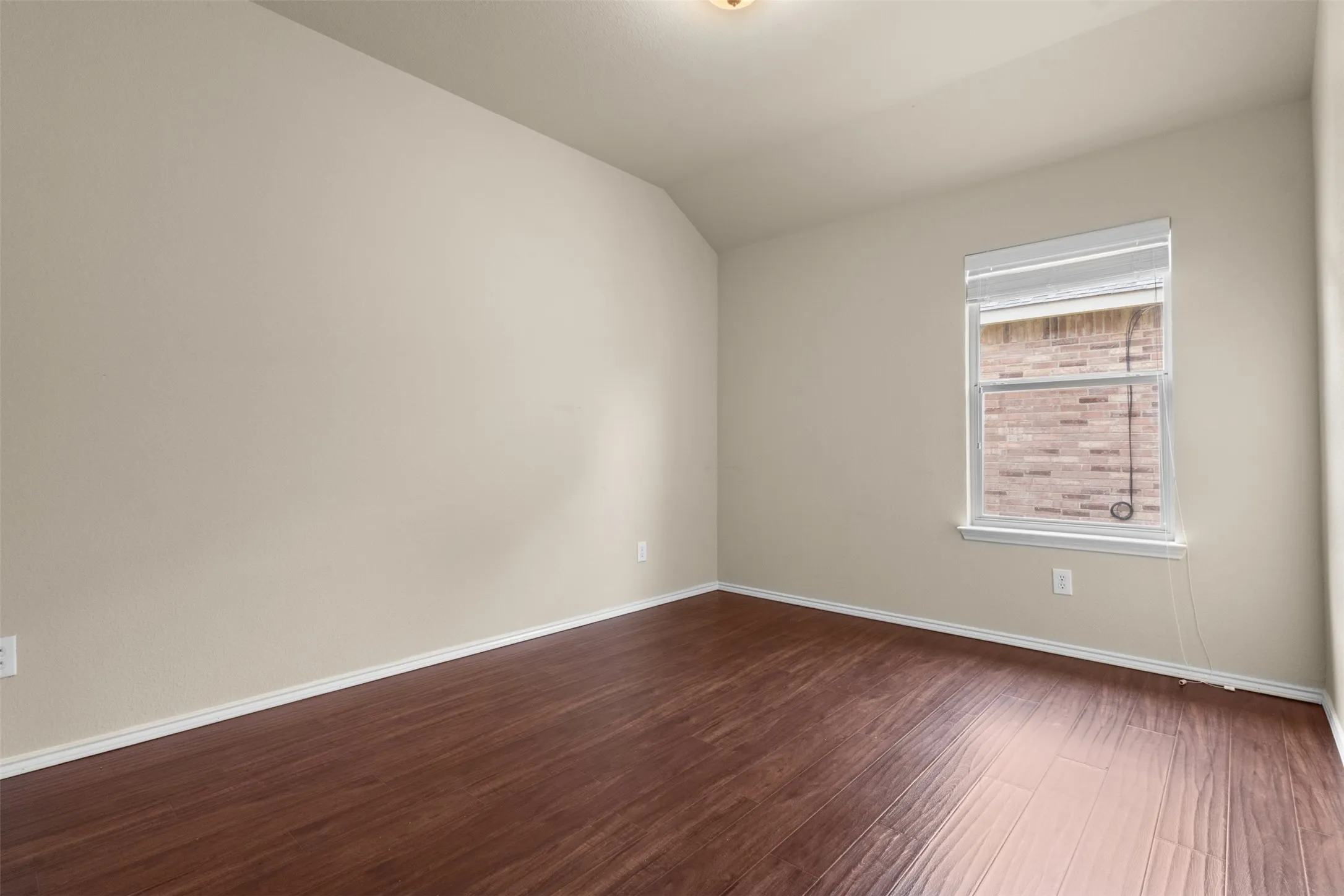 Wood-finish flooring, neutral wall paint, single window with blinds, white trim, and a ceiling-mounted light fixture