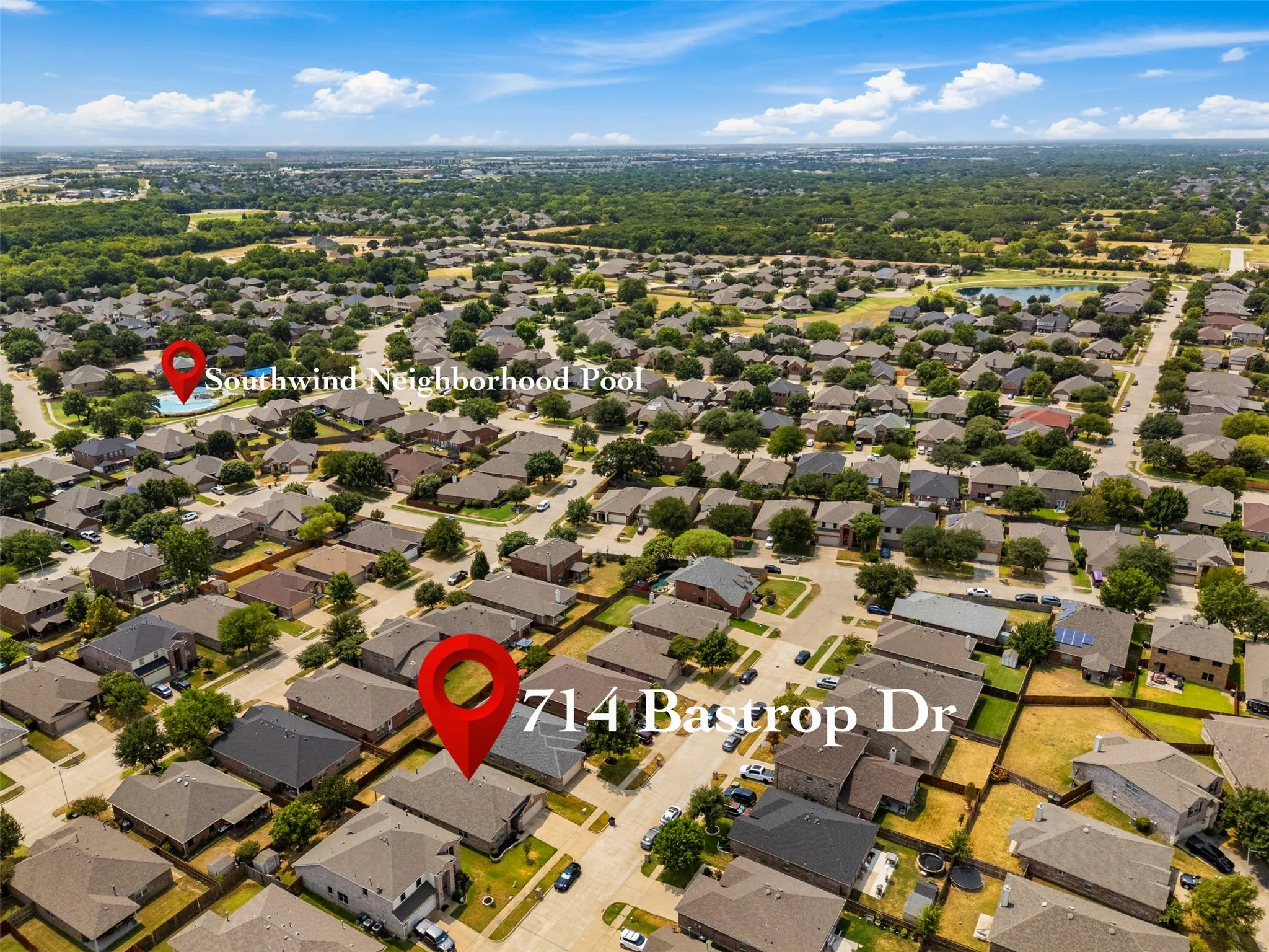 Aerial perspective of a residential neighborhood featuring numerous single-story homes with dark-toned roofs, mature trees lining streets, and a prominent neighborhood pool
