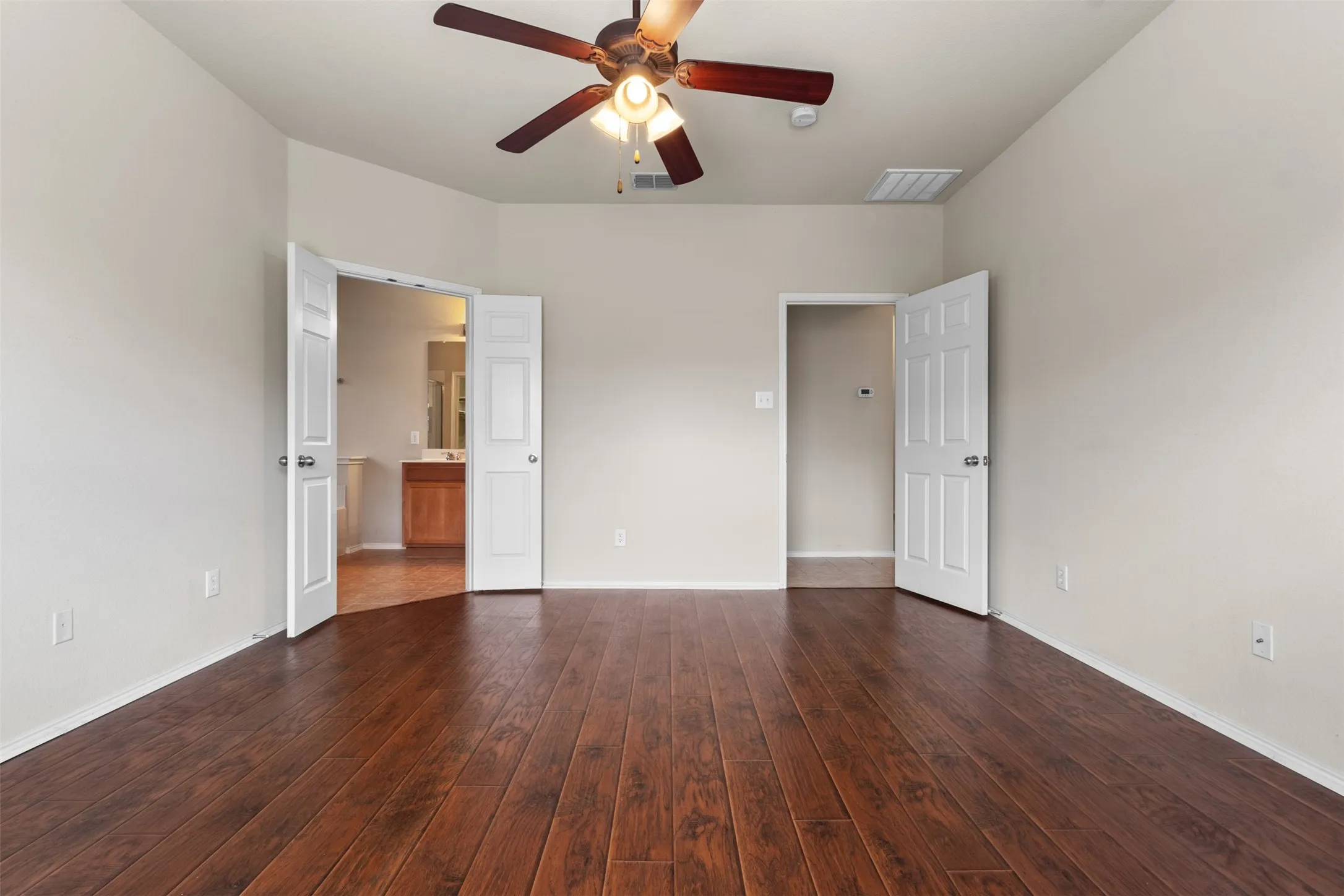 Wood-finish flooring throughout, ceiling fan with integrated lighting, and white paneled doors