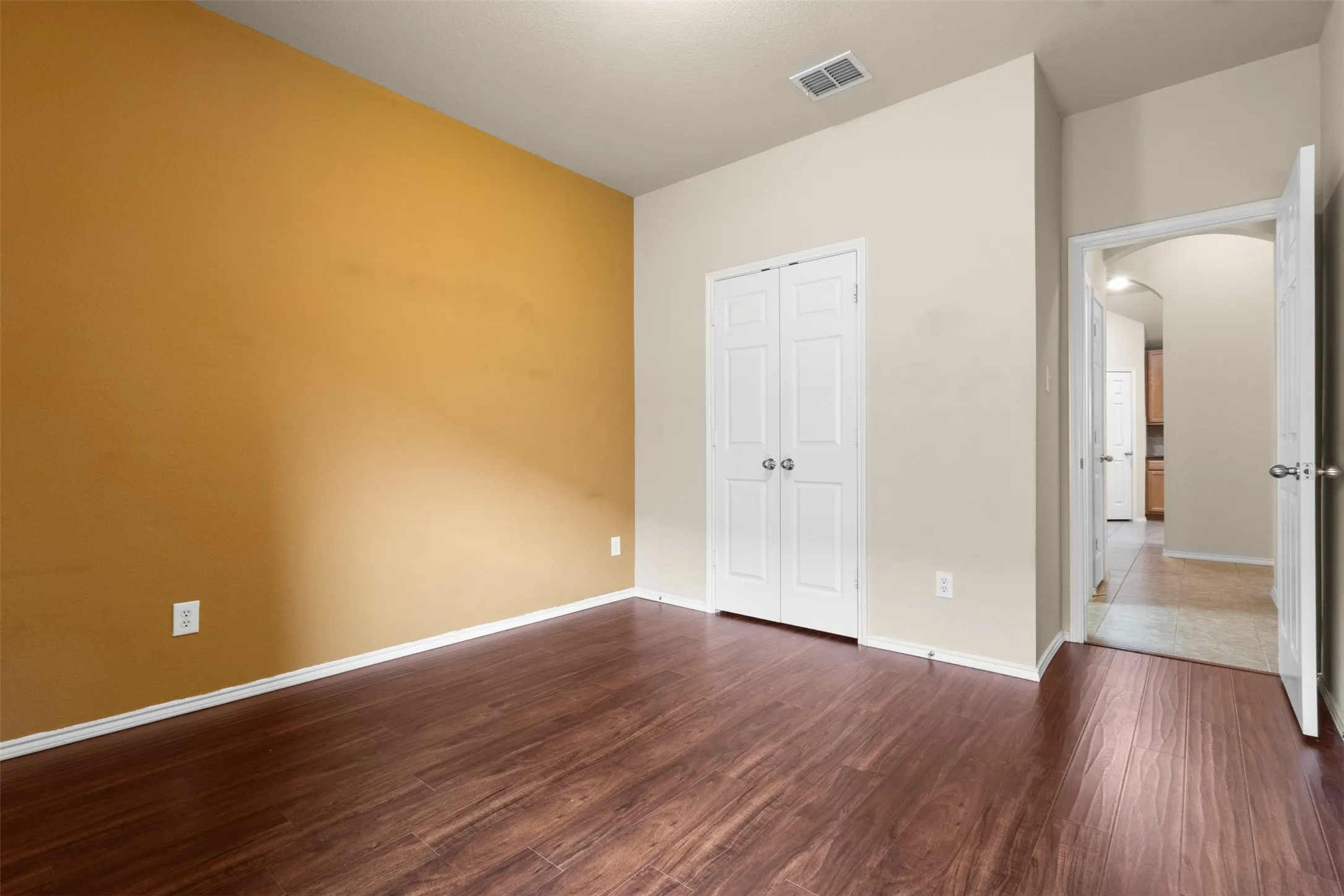 Wood-finish flooring, bi-fold closet doors, ceiling light fixture, and neutral wall tones
