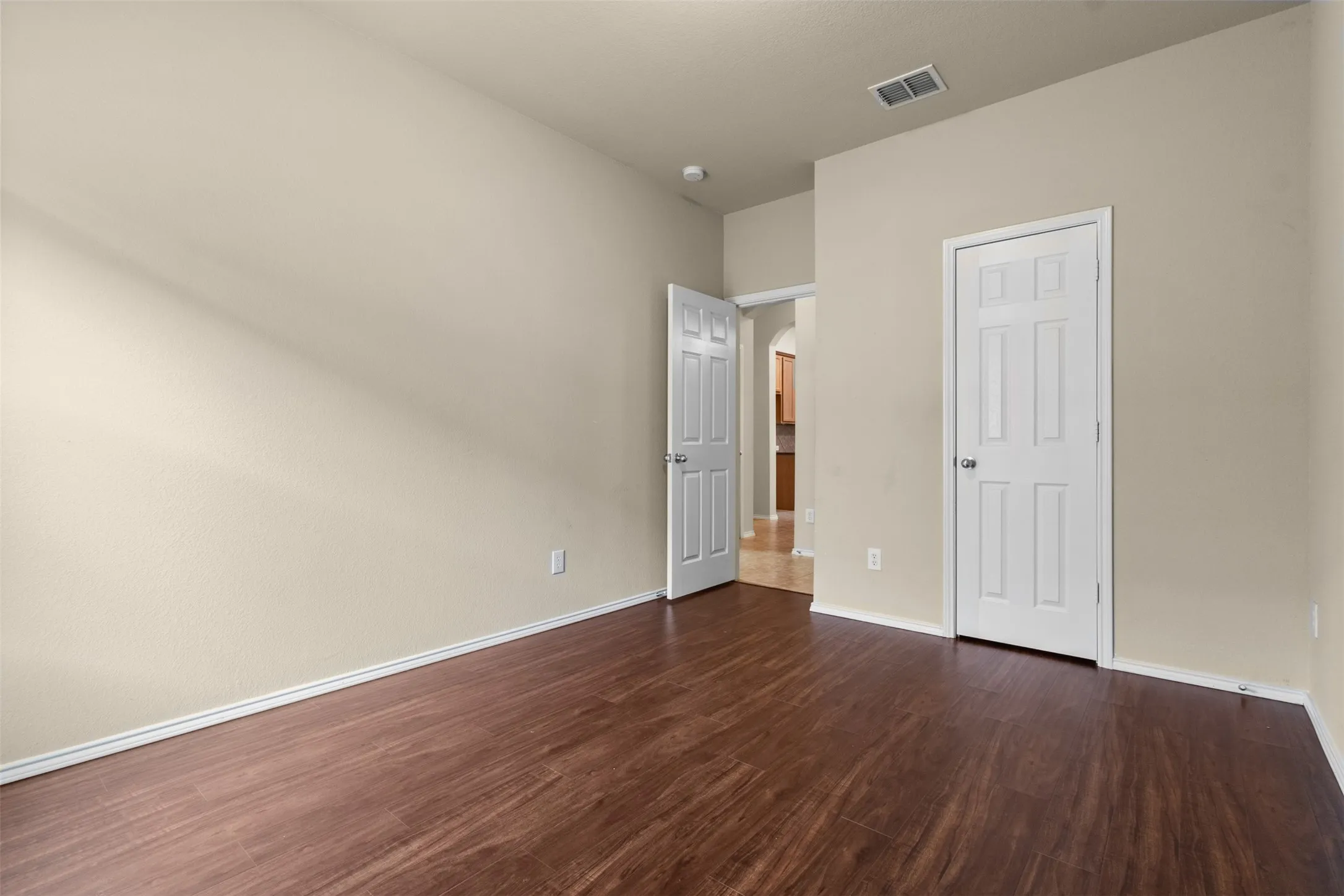 Wood-finish flooring with neutral wall tones and white paneled doors