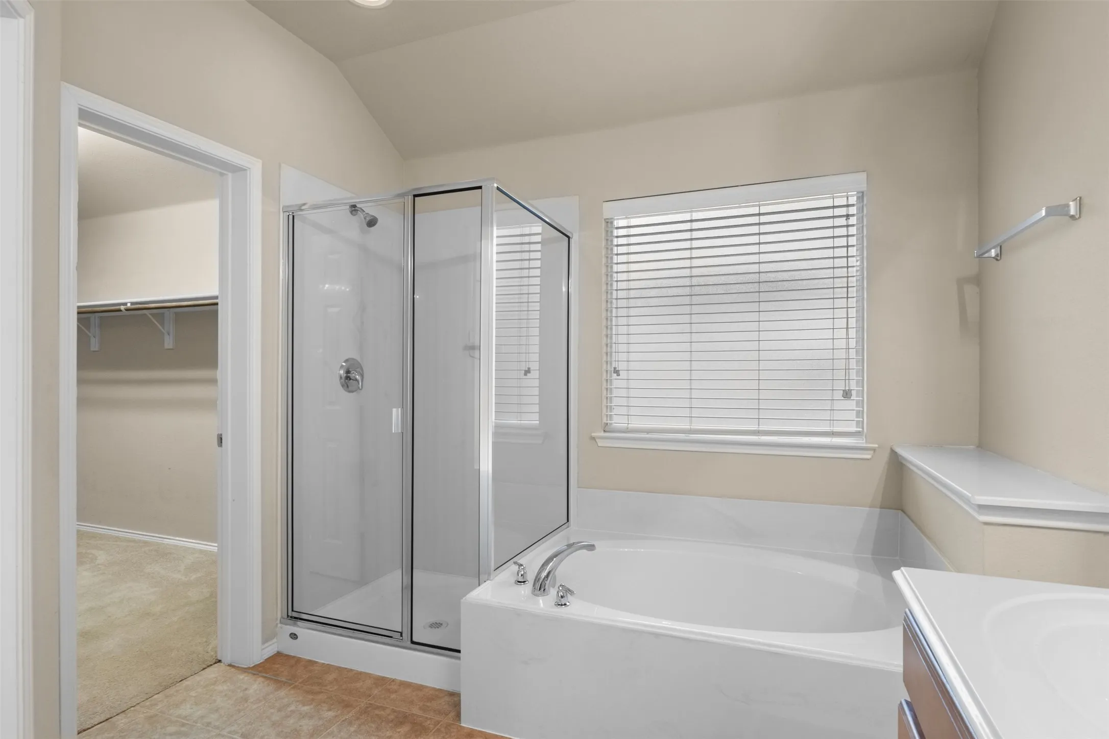 Enclosed glass shower, built-in bathtub with deck, window with blinds, and recessed lighting