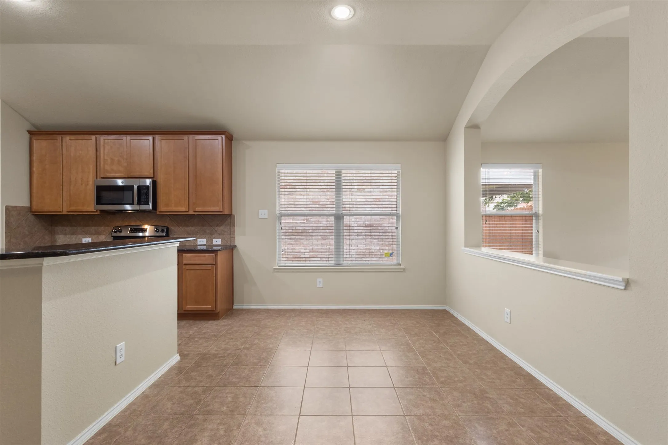 Kitchen area featuring wood cabinetry, stainless steel microwave and range, and dark countertops