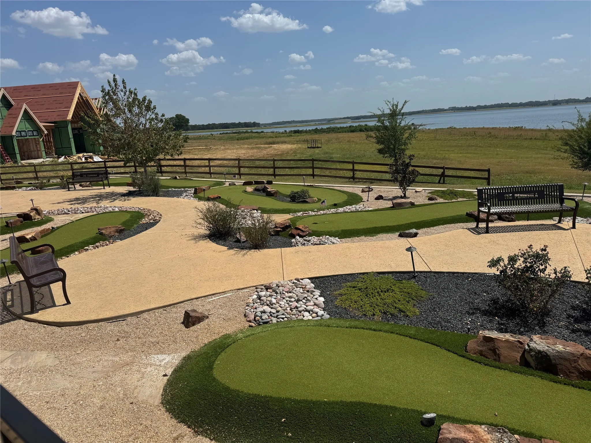 Miniature golf course with multiple greens, surrounded by gravel pathways and decorative rock landscaping