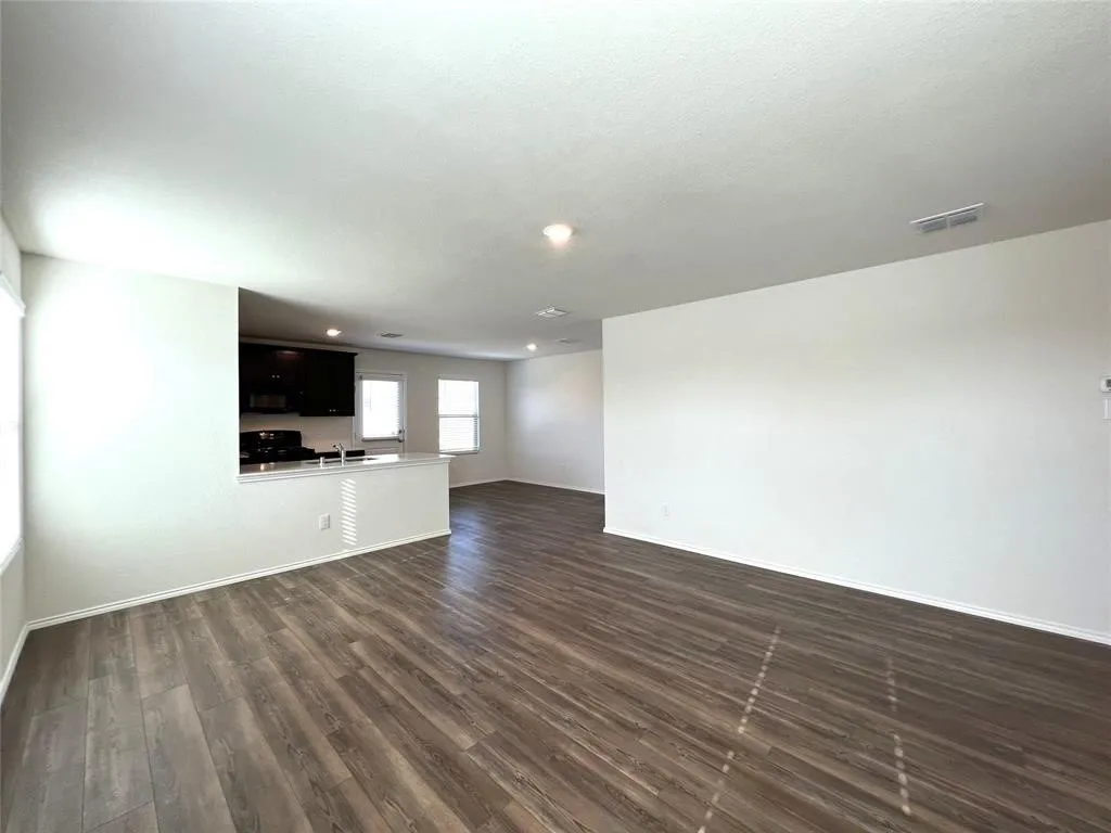 Open-concept living area featuring wood-finish flooring, recessed lighting, and a kitchen pass-through with a breakfast bar