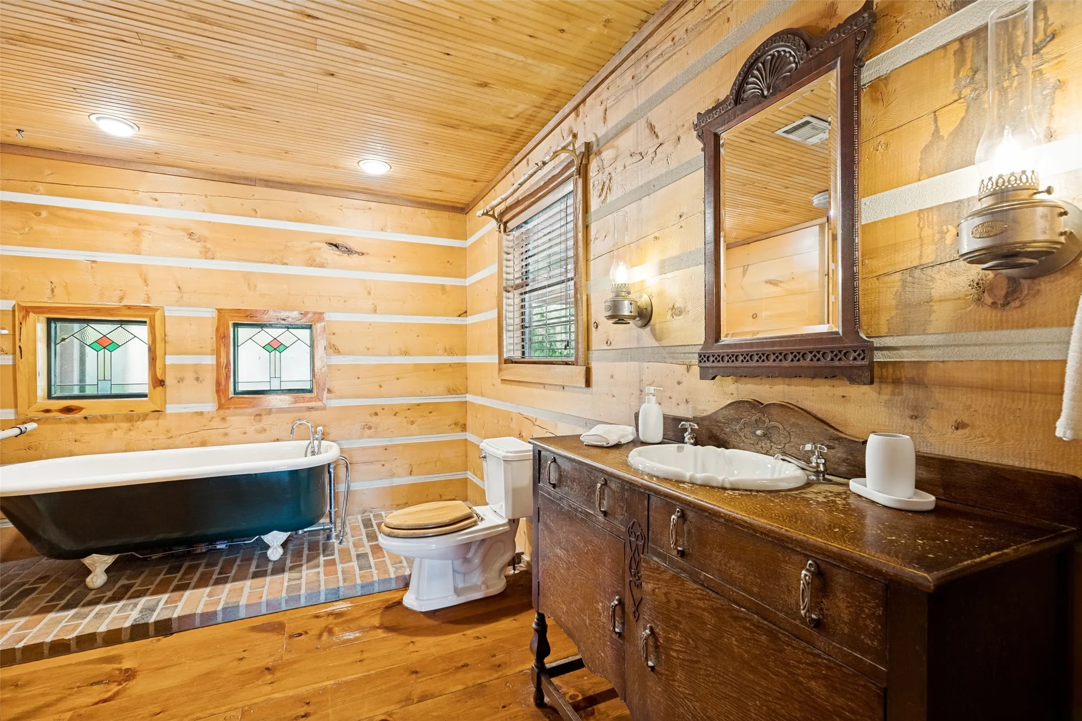 Primary Bathroom with Antique Vanity and Claw Foot Tub on Brick Platform