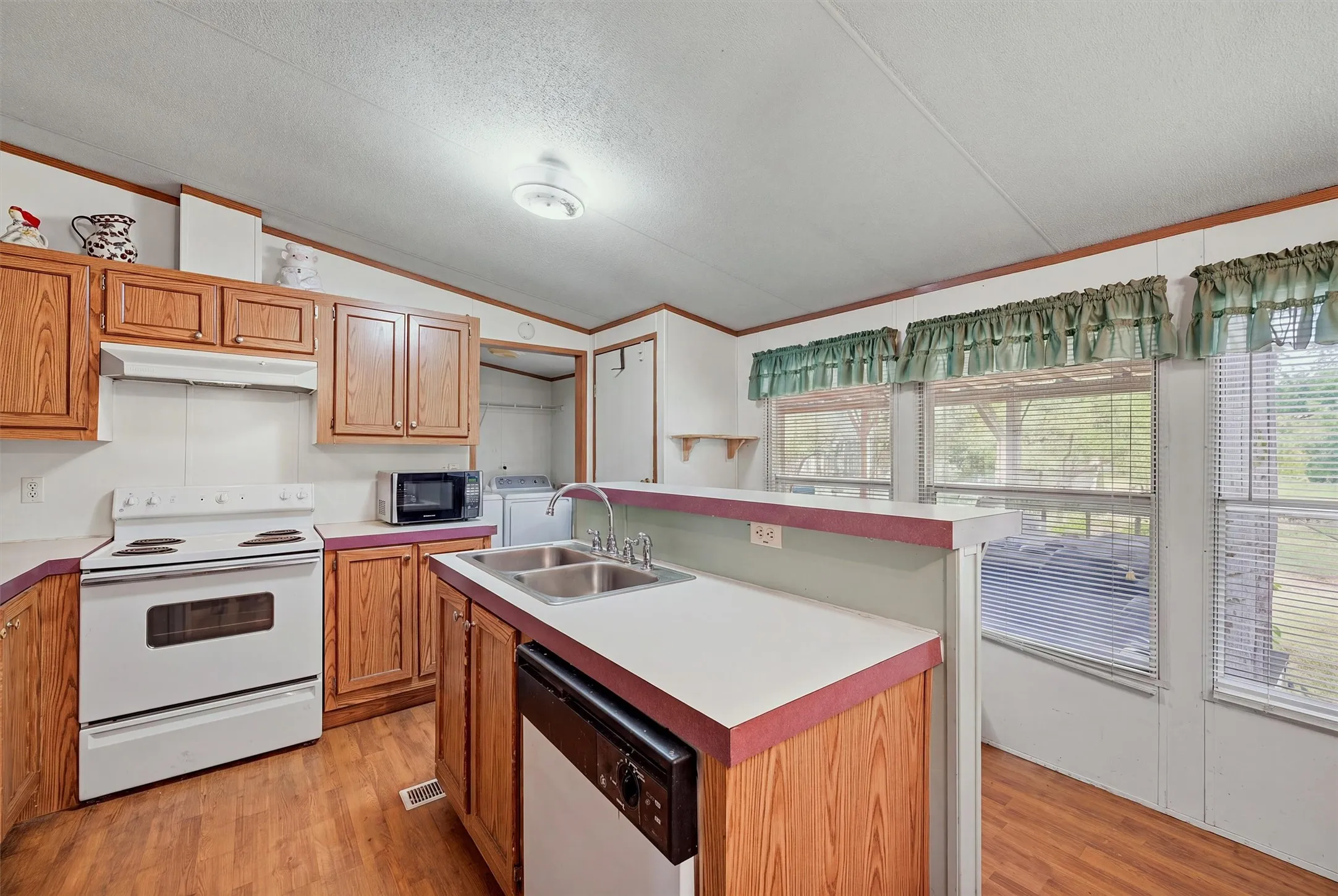 AI enhanced - Kitchen featuring wood-finish flooring, wood cabinetry, white countertops, and a double basin sink with a single-handle faucet