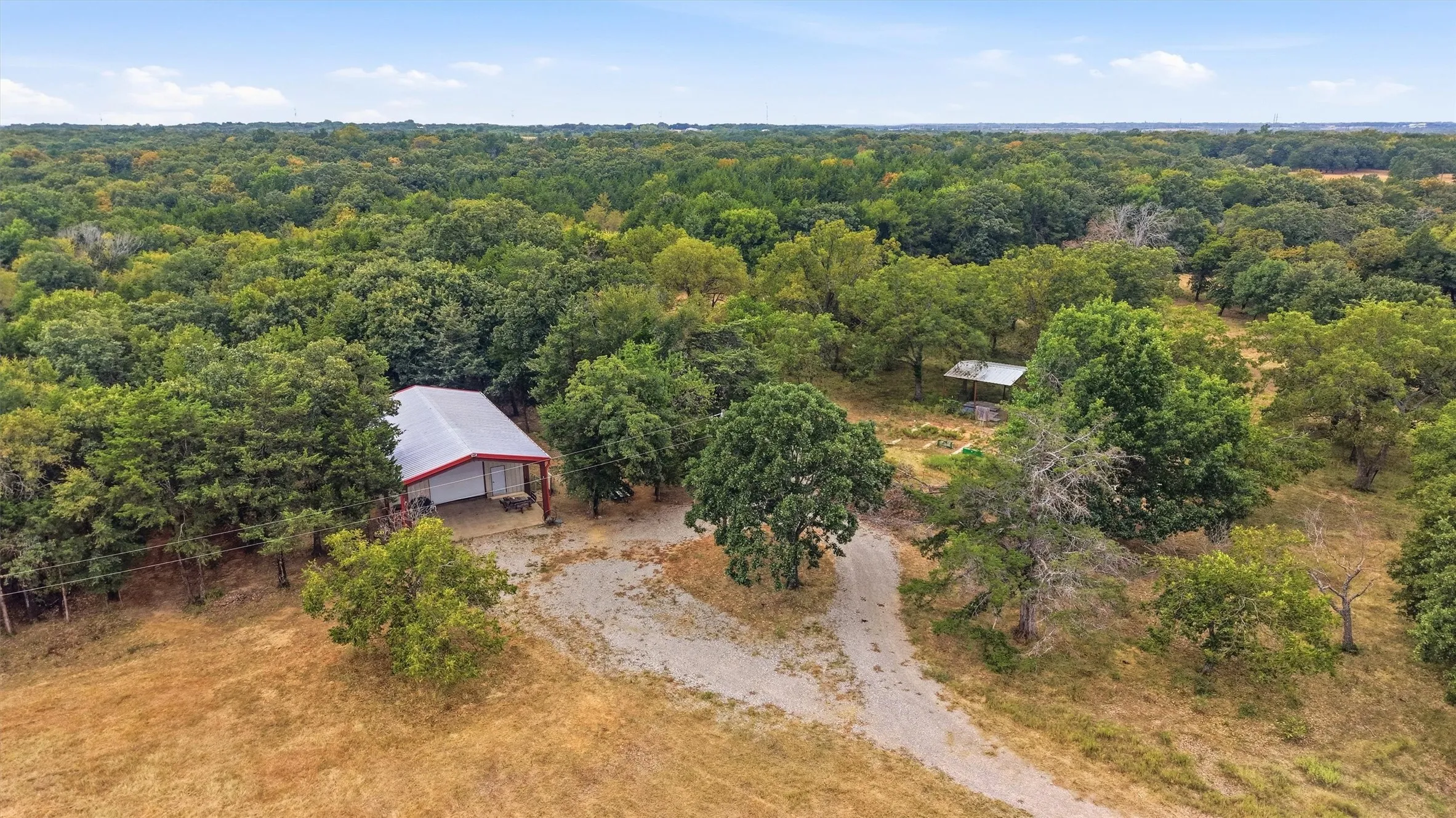 1200 square food workshop with a metal roof and red trim, surrounded by mature trees