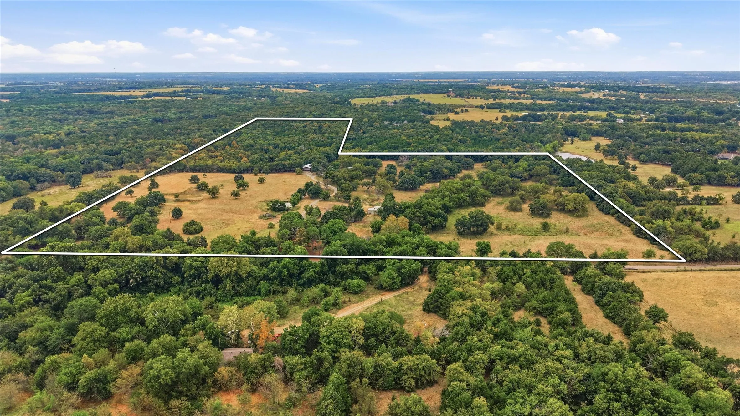 Expansive open pasture, mature trees, wooded areas, and overall acreage, with approximate property boundaries highlighted.