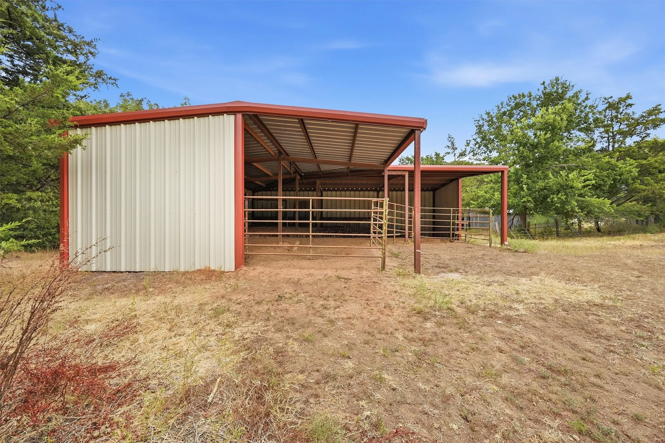 Loafing Shed, built in 2017 with an open-air covered section, red-trimmed roofline, and integrated fencing