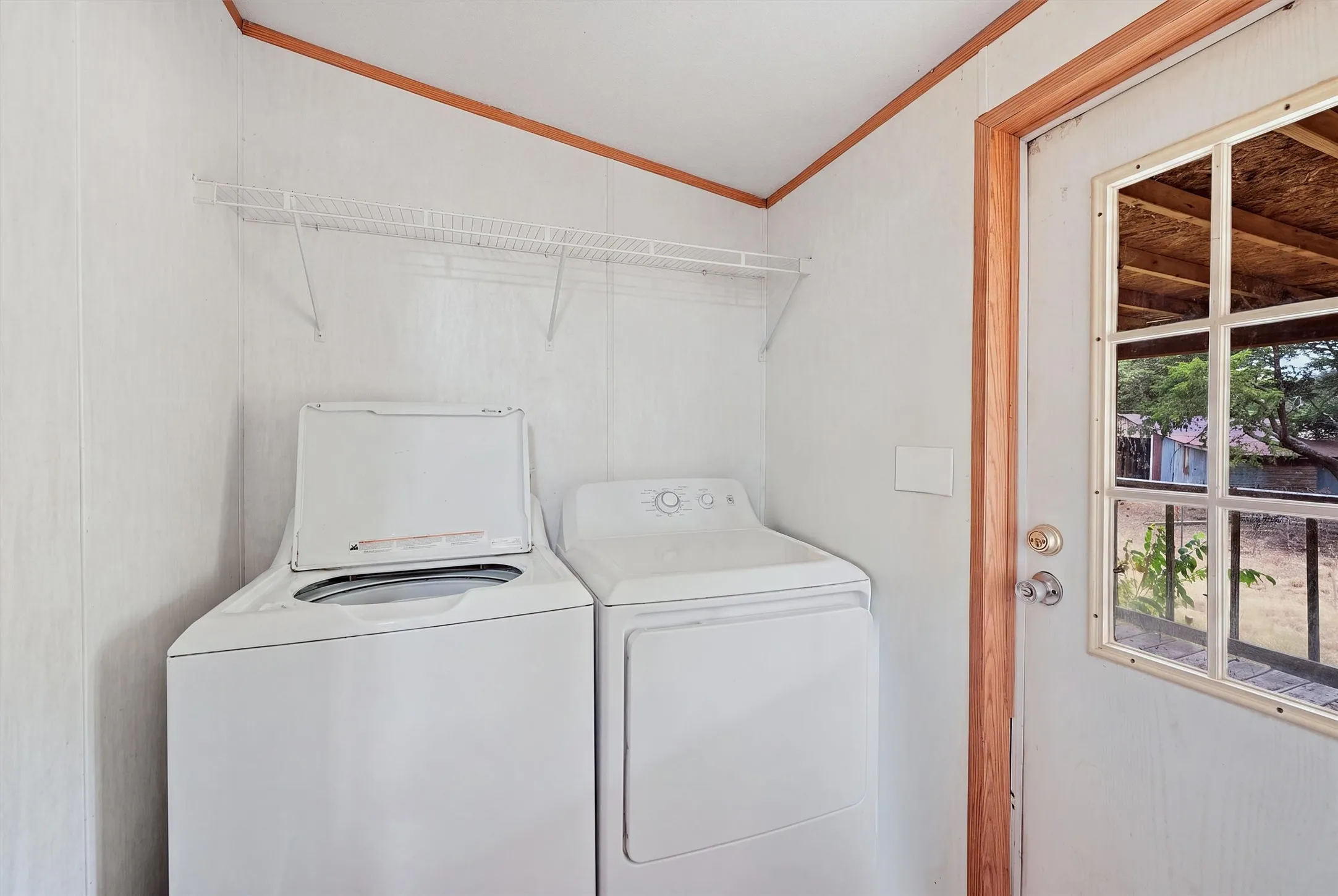 AI enhanced - Laundry area with a top-load washing machine, a front-load dryer, and an overhead wire shelf