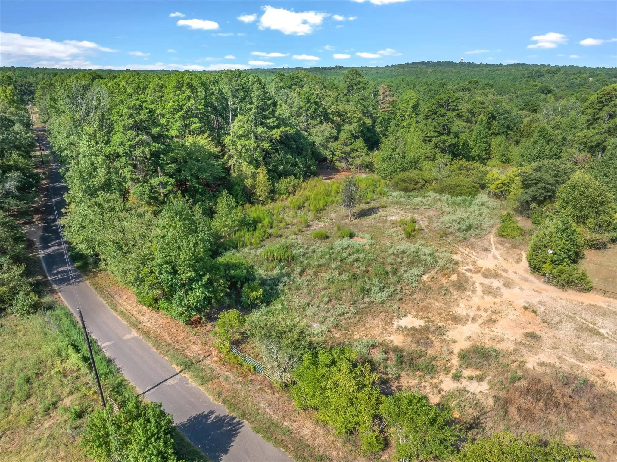 Paved road access with extensive tree coverage and varied topography