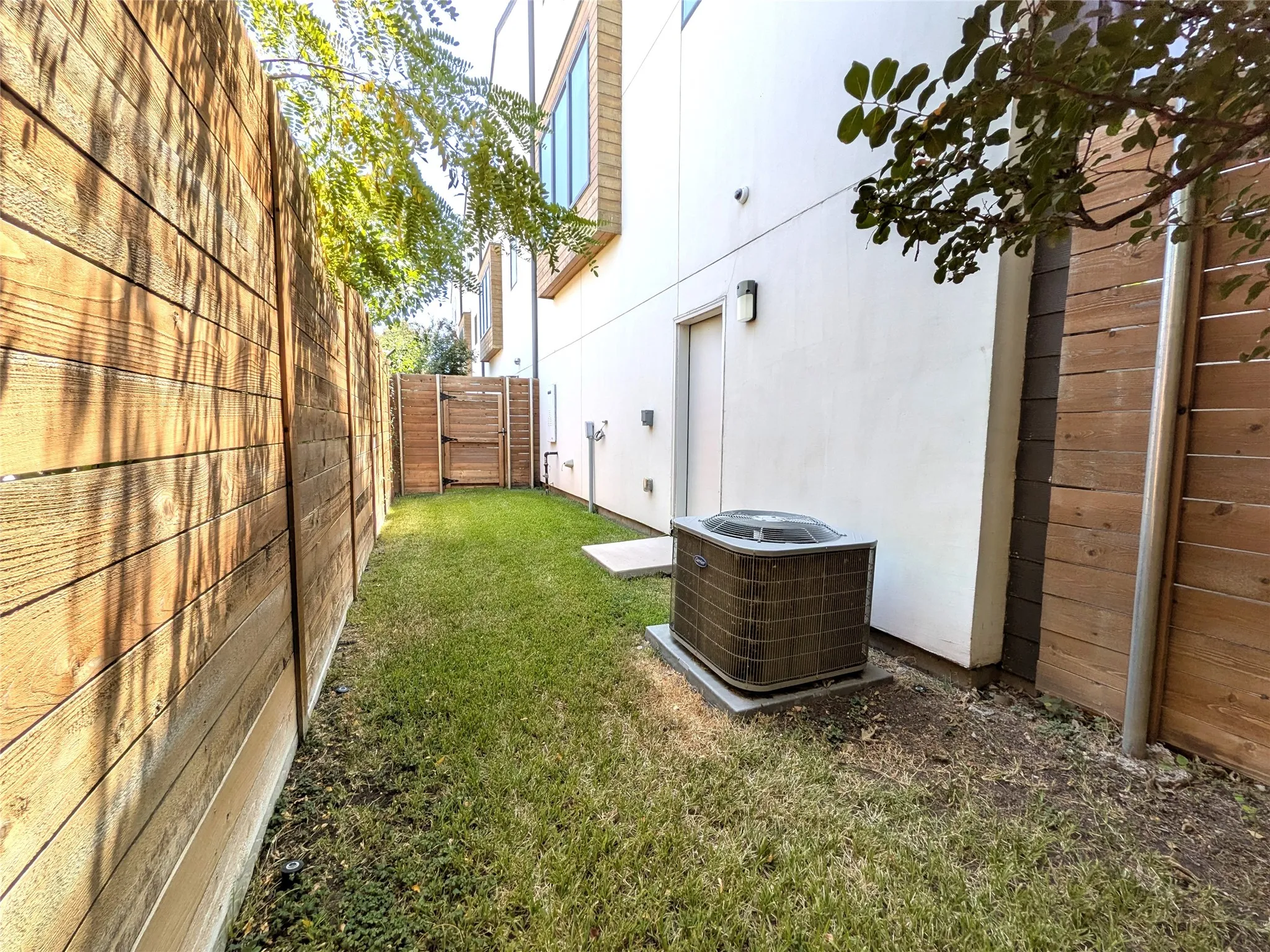 Private outdoor space featuring a wood fence, a grass lawn, and an exterior door