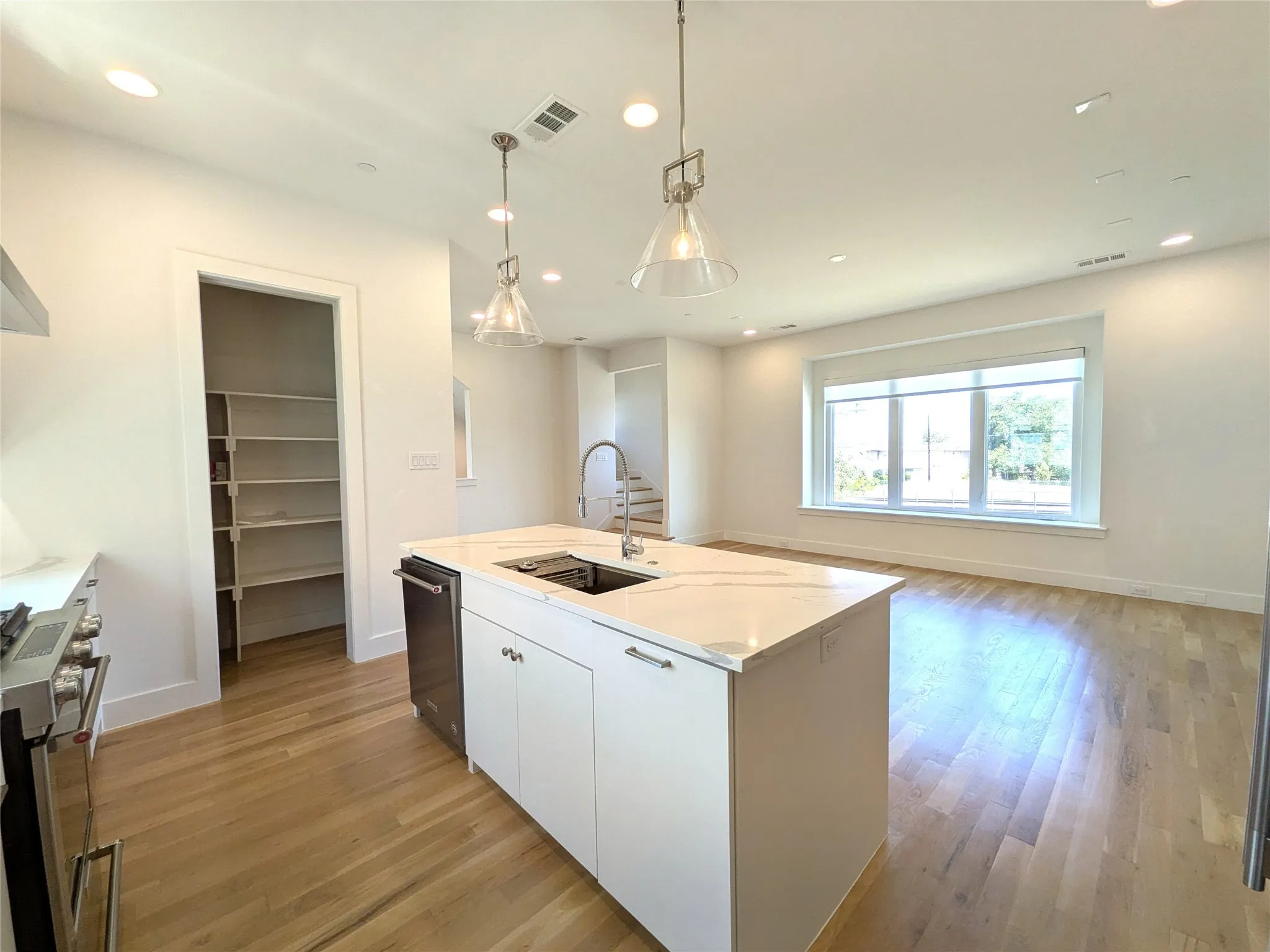 Open-concept living area with wood-finish flooring, recessed lighting, and a large window
