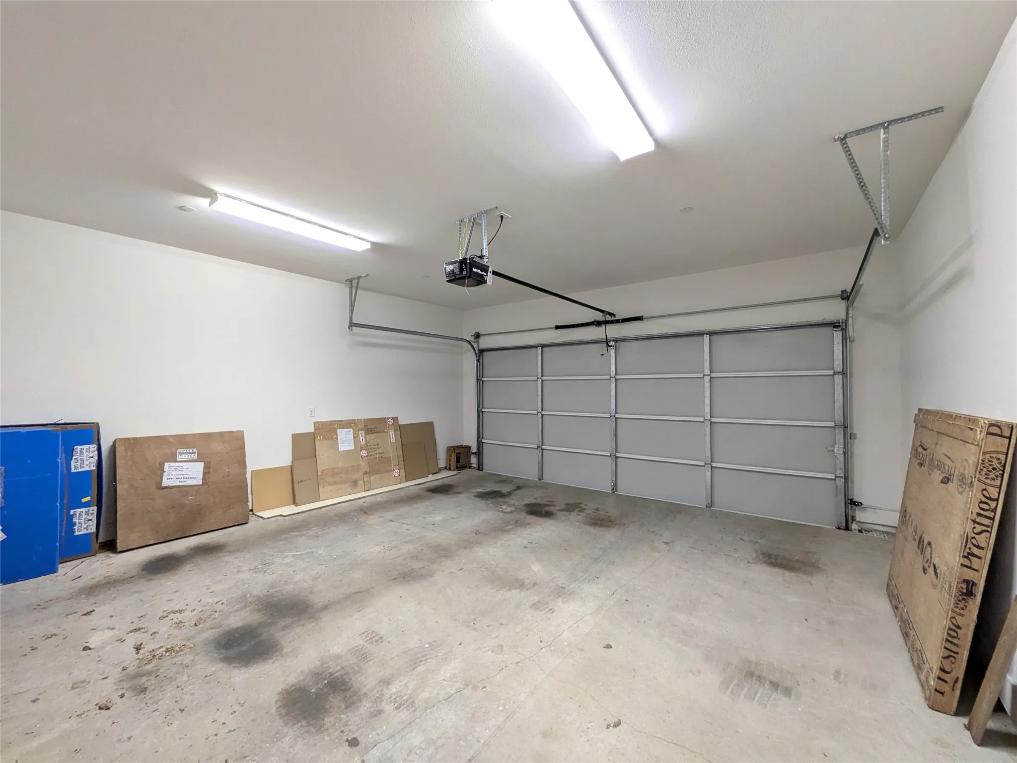 Garage with concrete flooring, fluorescent ceiling lighting, and an automatic garage door opener