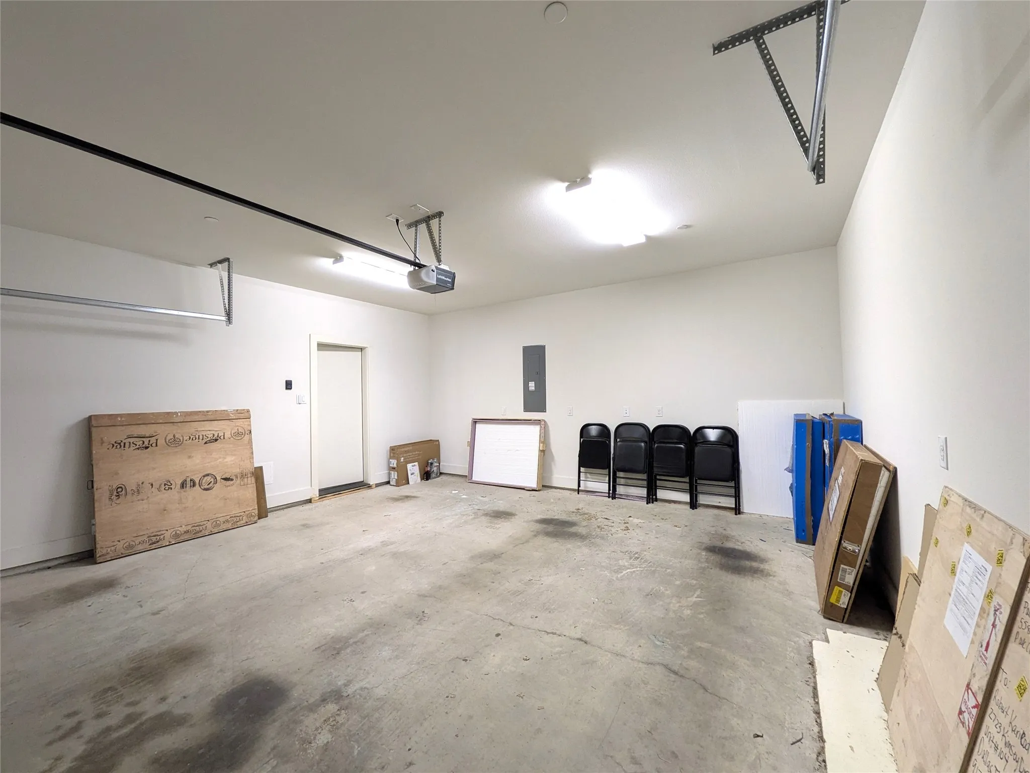 Attached garage featuring a concrete floor, white painted walls, and overhead lighting