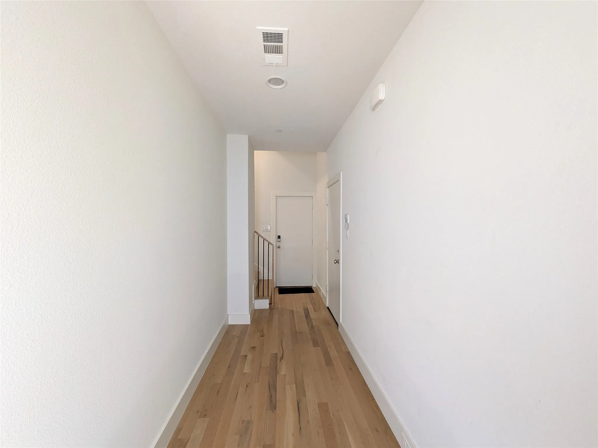 Wood-finish flooring leading to an entryway with a white door