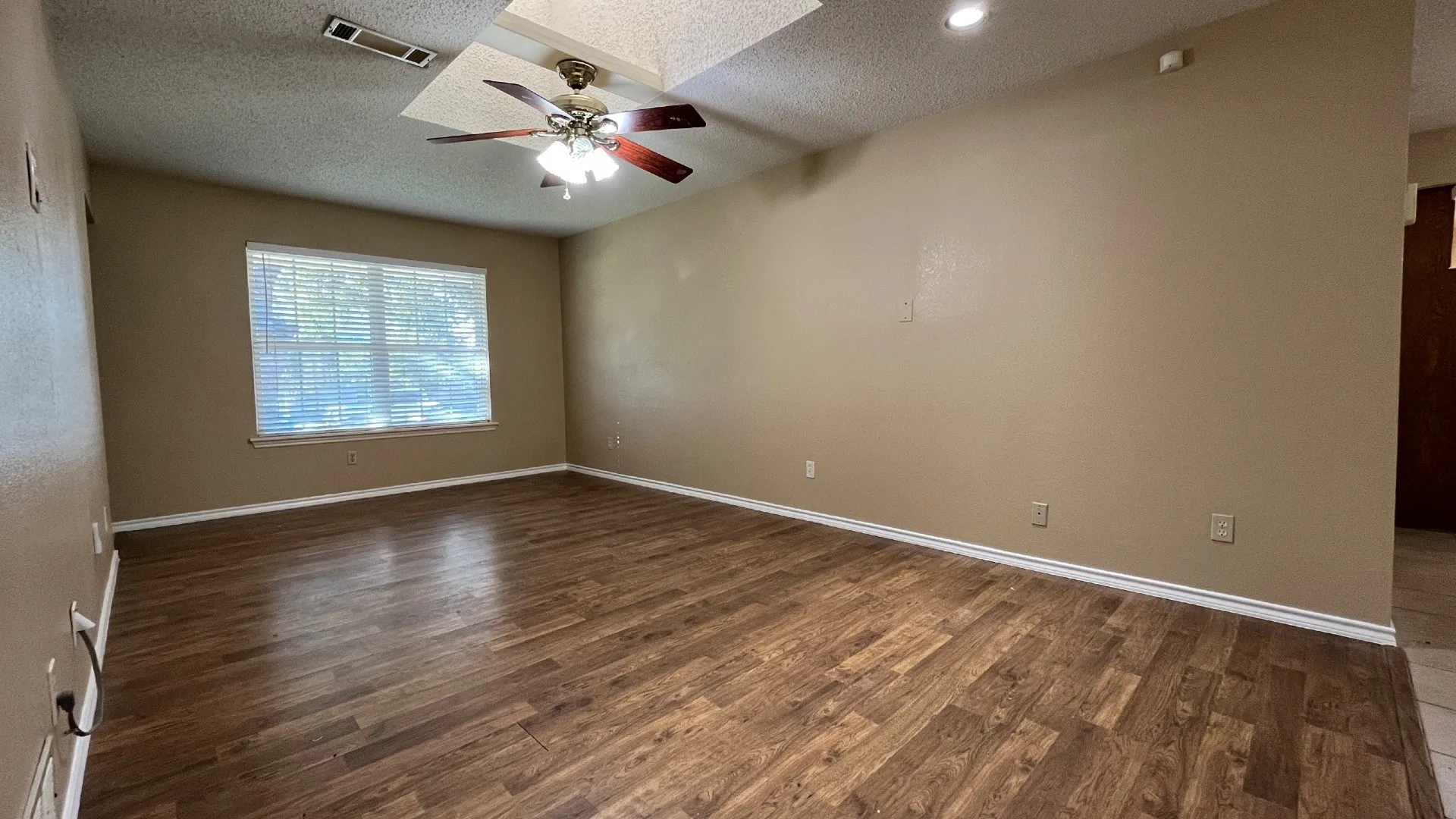 Wood-finish flooring throughout, tray ceiling, recessed lighting, and a ceiling fan with integrated lighting