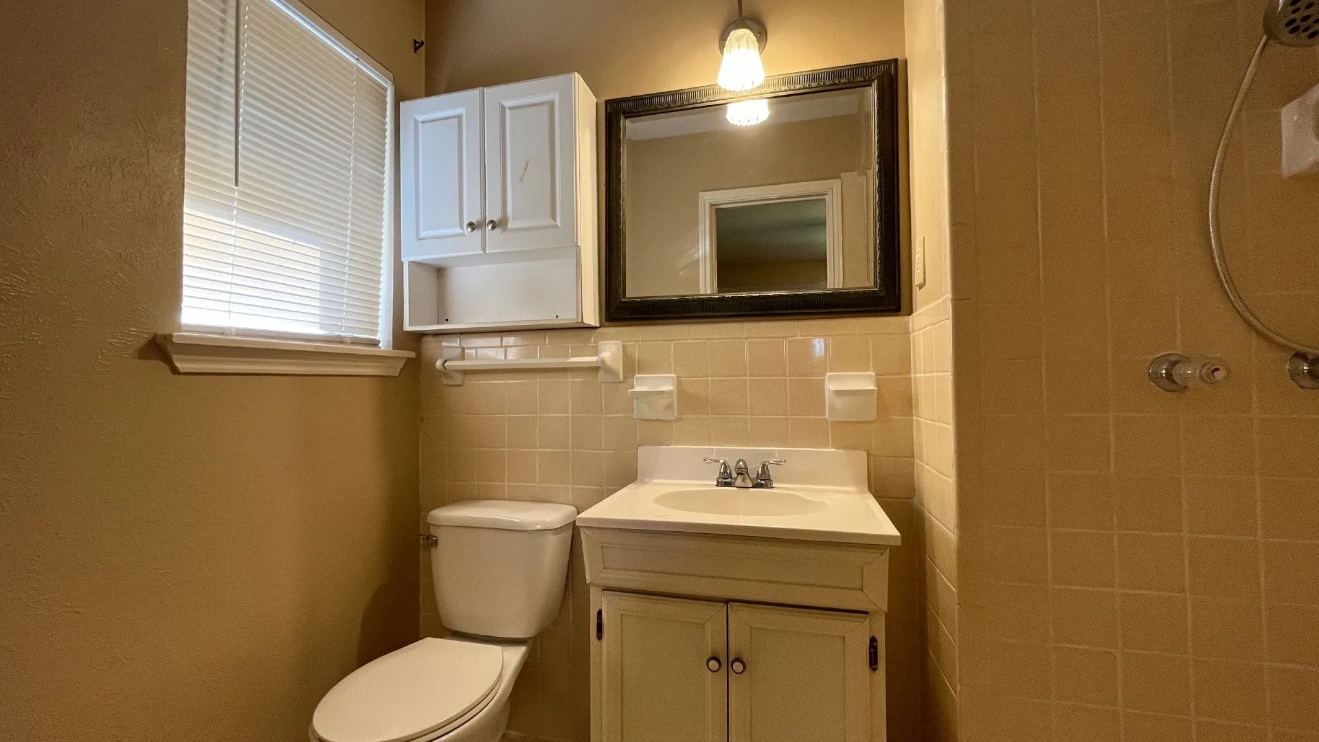 Vanity with an integrated sink, framed mirror, and tiled walls
