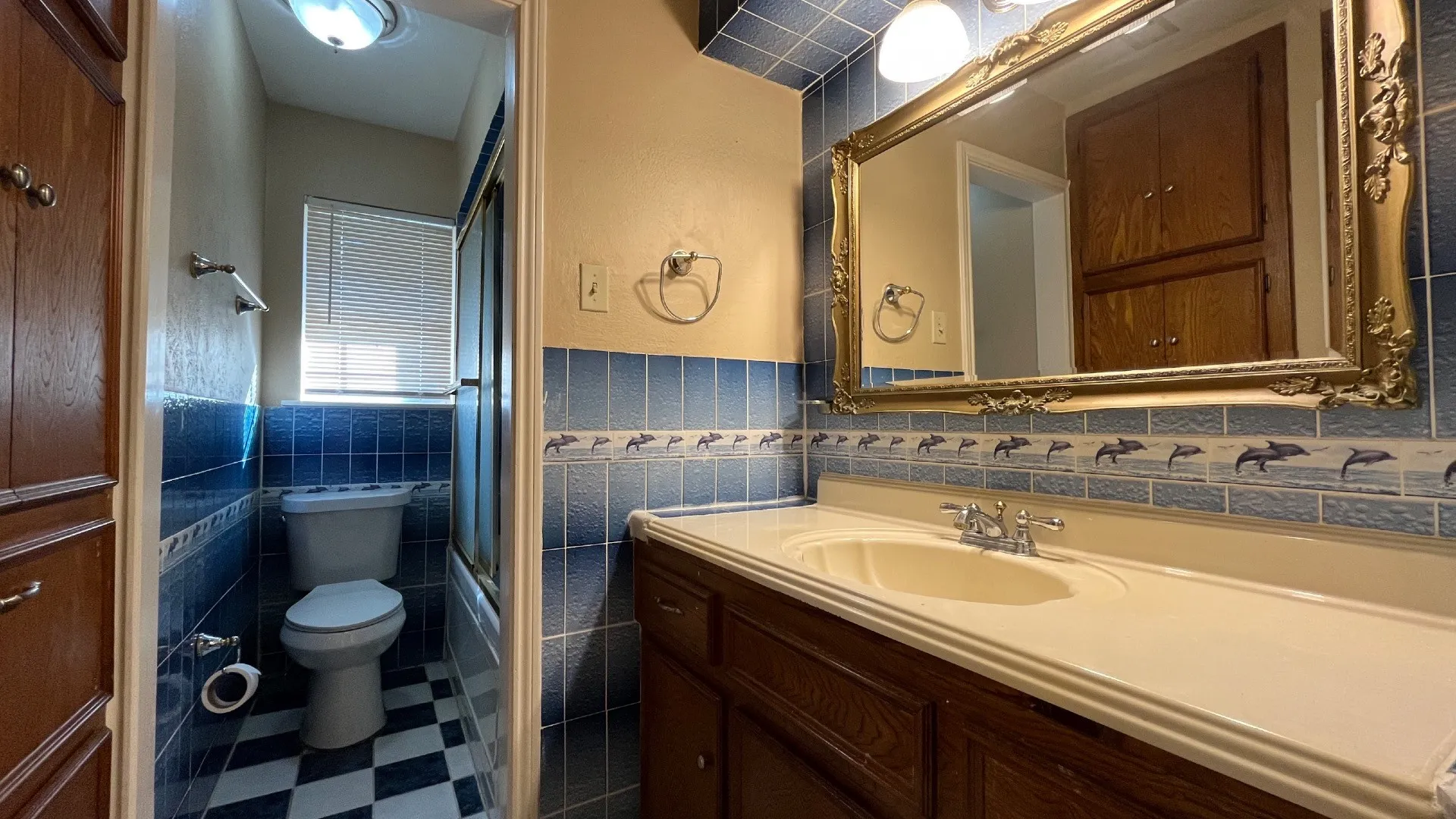 Bathroom featuring a vanity with an integrated sink, a large framed mirror, built-in cabinetry, and blue wall tiling