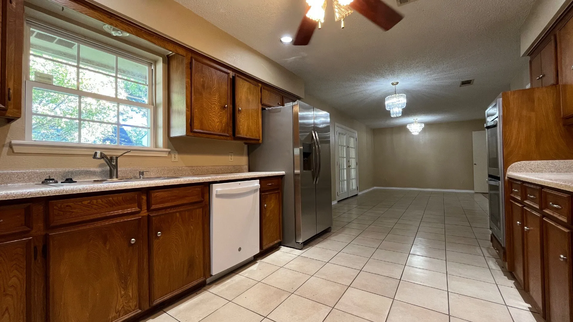 Kitchen featuring wood cabinetry, stainless steel appliances, a double basin sink, and tile flooring