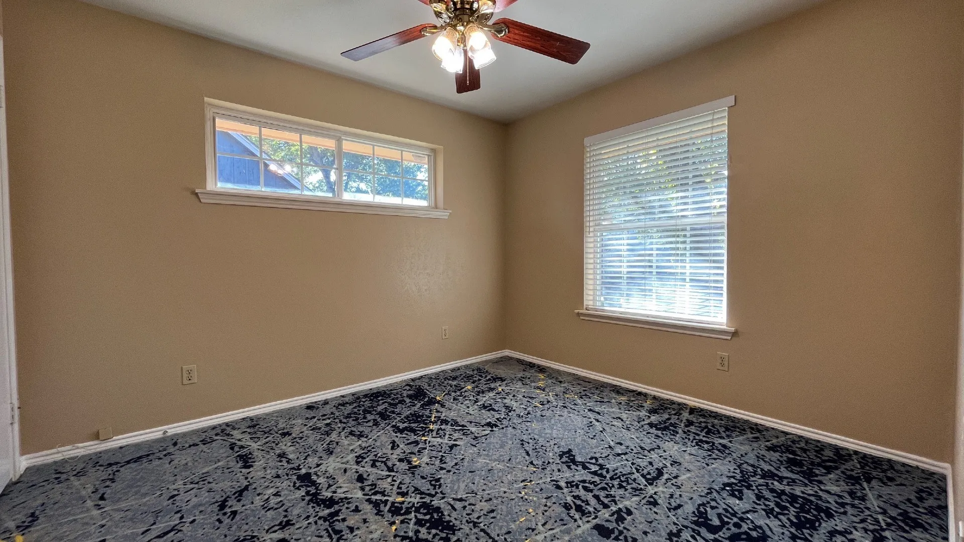 Ceiling fan with a wood-finish and bronze-tone fixture, large window with blinds, and a transom window
