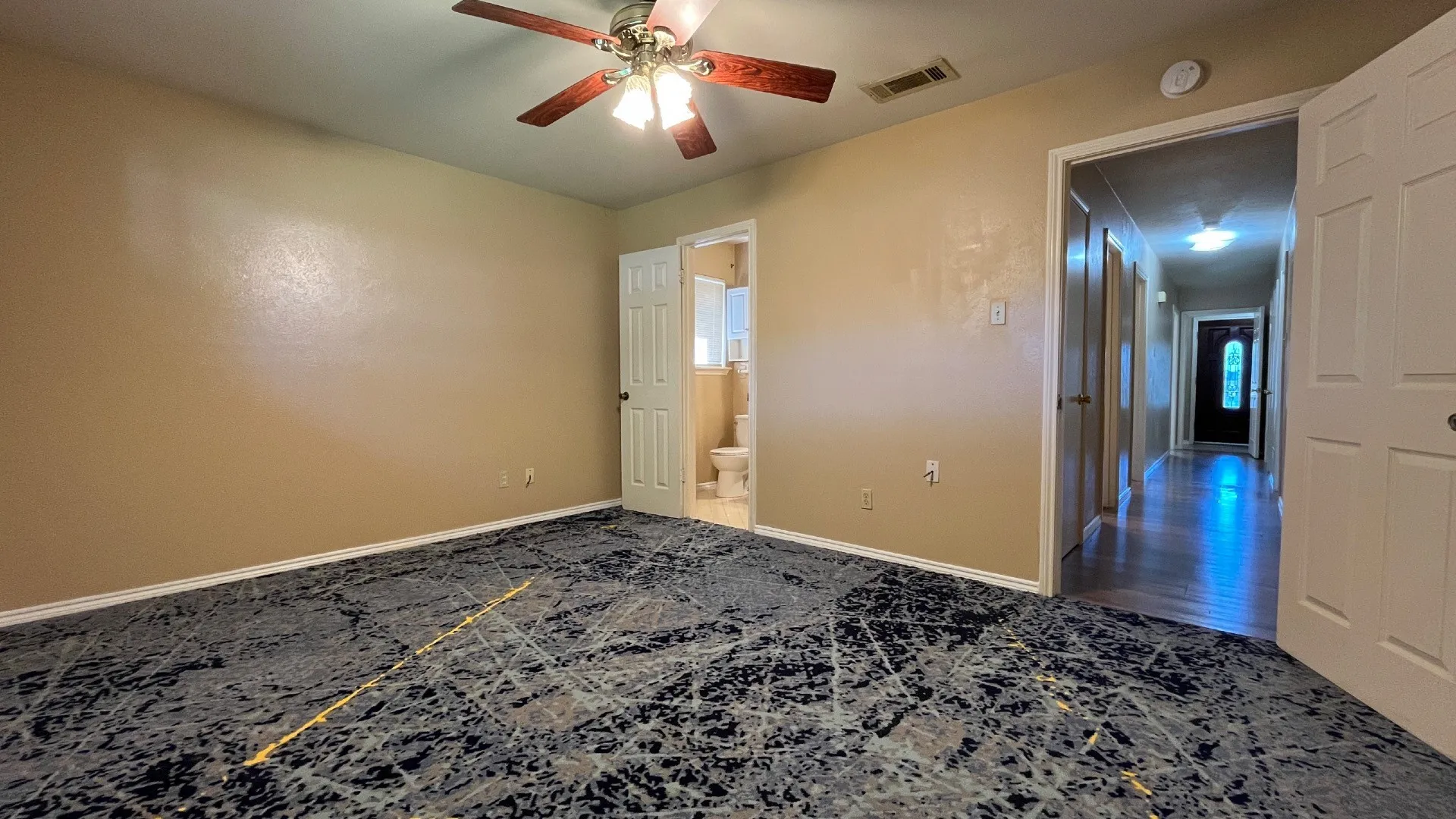 Spacious room with patterned carpeting and a ceiling fan