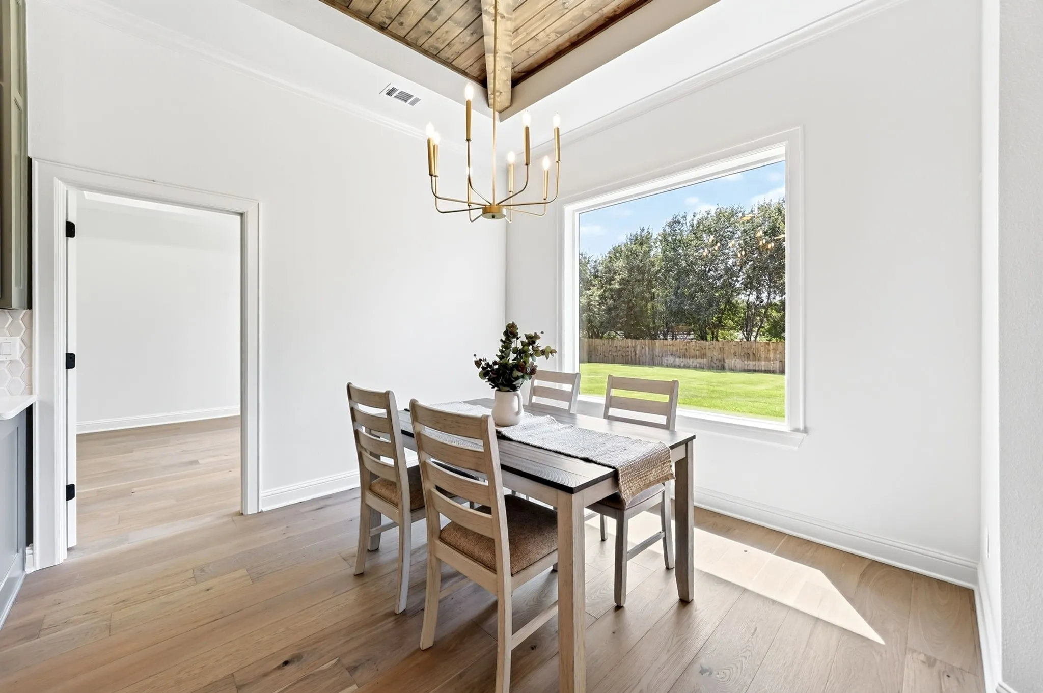 Dining area featuring decorative wooden beams, ample natural lighting with views of the backyard.