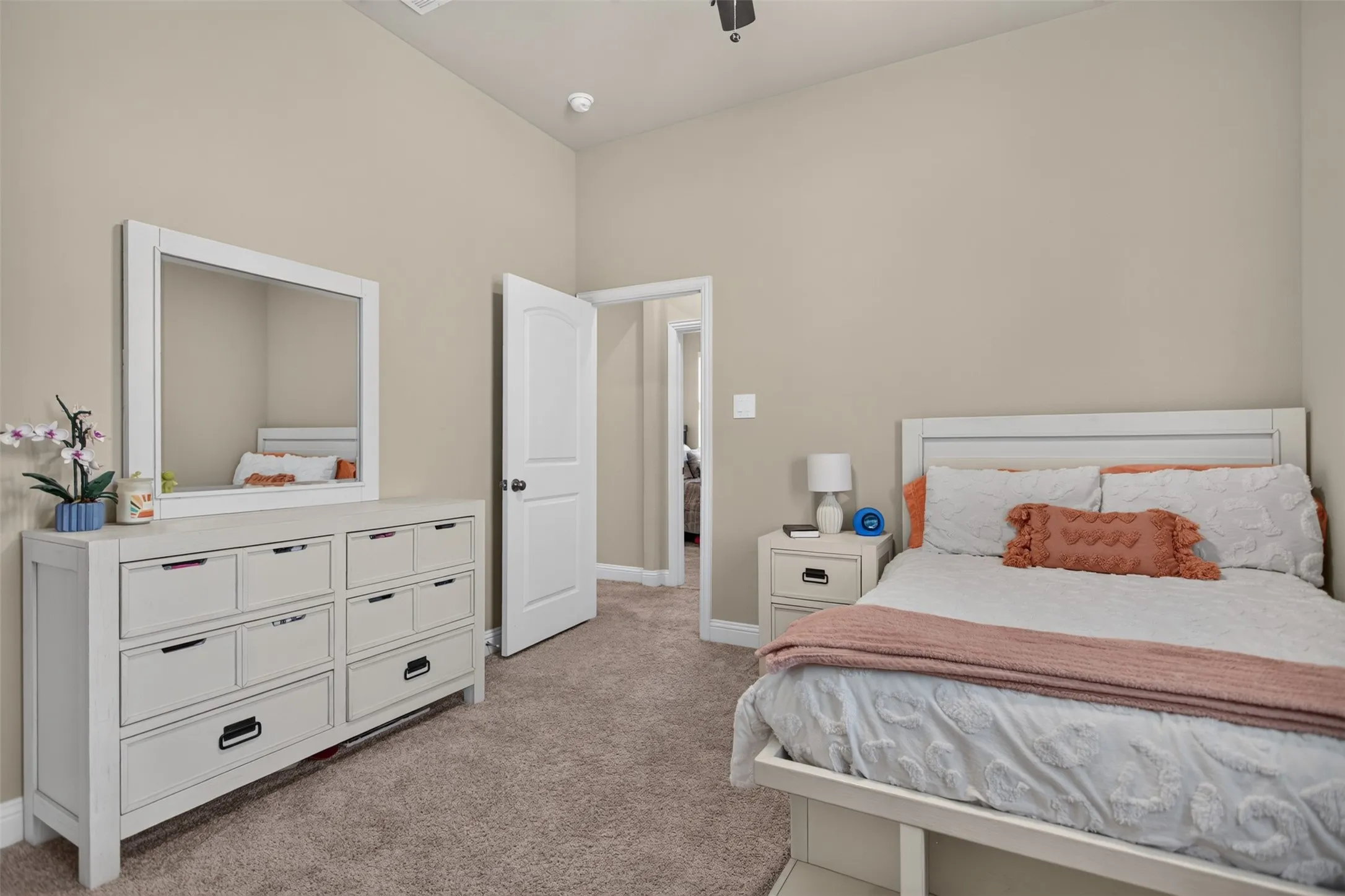 Plush carpet flooring, neutral wall tones, and a vaulted ceiling create an inviting atmosphere